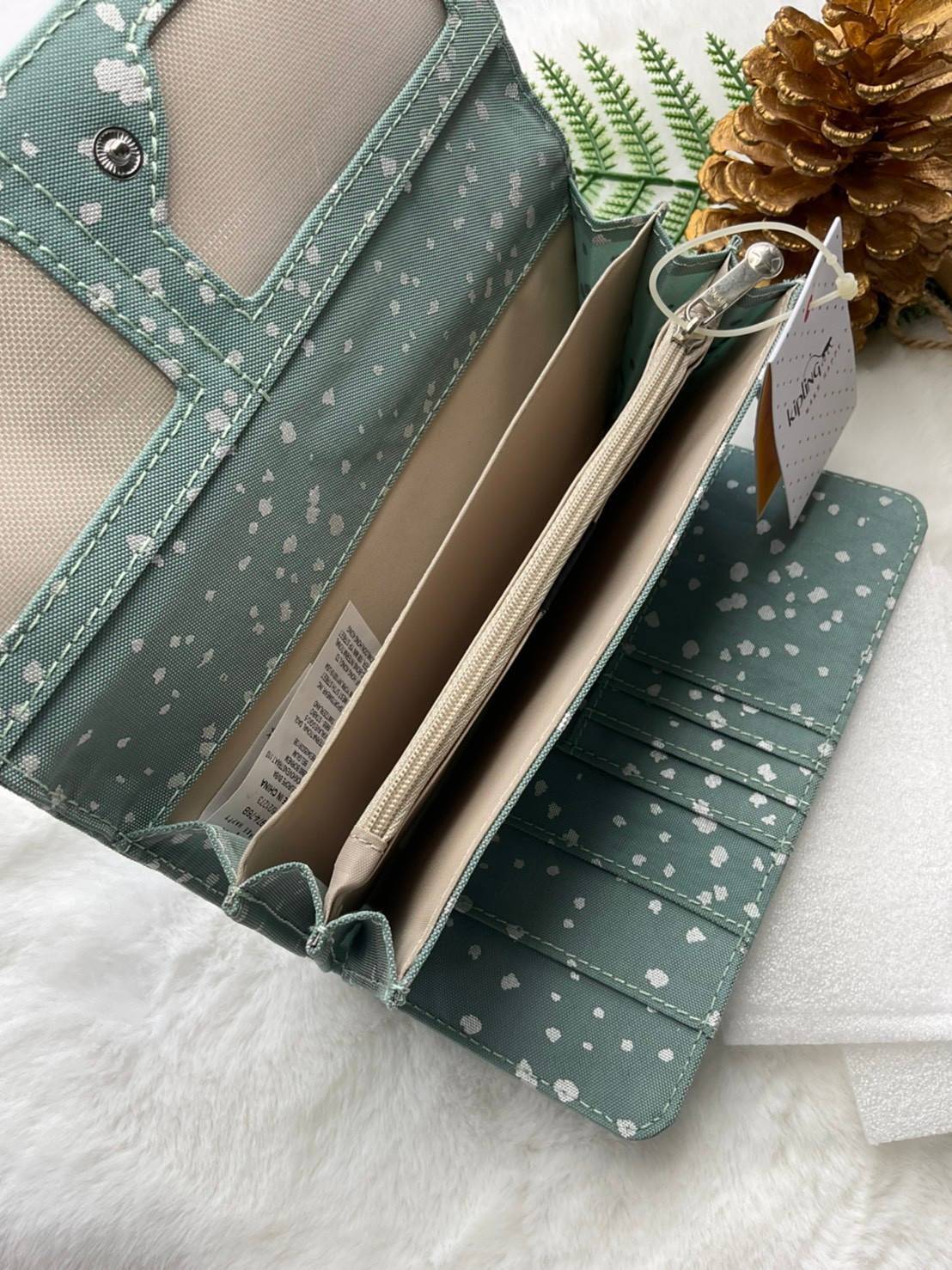 กระเป๋าสตางค์ยาว 3 พับตอน Kipling Brownie long tri-fold wallets กระเป๋าสตางค์ยาวแบบ3พับตอน วัสดุกันน้ำ เปิดปิดด้วยกระดุมแป๊ก มีช่องใส่ธนบัตรหลายช่อง ช่องเสียบการด์ได้ถึง13ช่องลายจุด และใส่รูปภาพได้อีก2ช่อง ช่องซิปใส่เหรียญ ช่องธนบัตร 3 ช่อง ที่จับหัวซิปปั