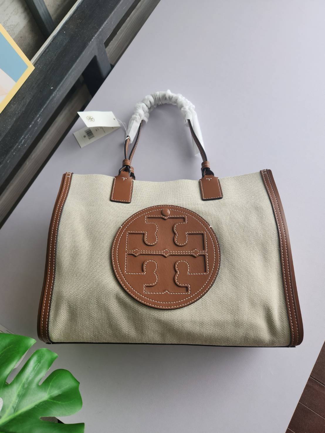 TORY BURCH ELLA CANVAS TOTE BAG กระเป๋าโท้ตน้ำหนักเบาของเราพร้อมป้ายโลโก้ Ella ทำจากผ้าใบที่ทนทานพร้อมรายละเอียดหนังและกระเป๋าด้านใน อเนกประสงค์ ทรงคลาสสิก และสร้างขึ้นอย่างสวยงามด้วยฝีมือช่างฝีมือ สายรัดแคบช่วยให้วางราบกับไหล่ได้อย่างสบาย เหมาะสำหรับทุกว