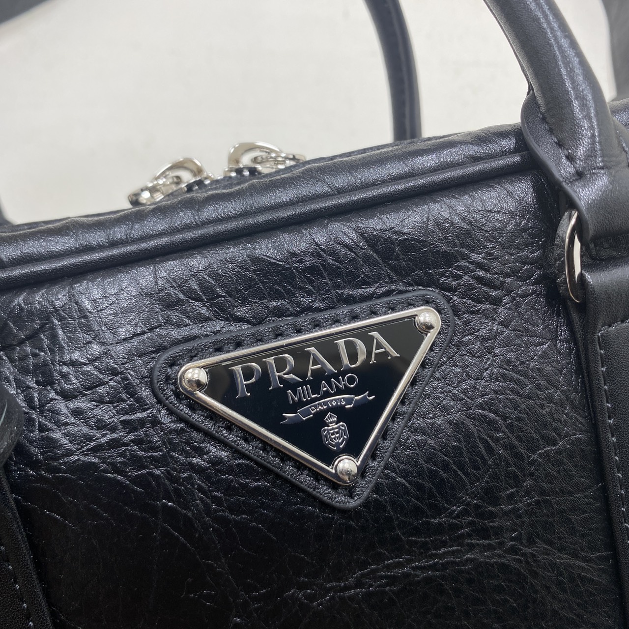 ORI หนังแท้ | Prada Small Top-handle Bag in Antique Nappa กระเป๋าสะพายพร้อมหูจับ งานหนังยับดีไซน์เอฟเฟกต์เท็กซ์เจอร์ที่มีเสน่ห์สไตล์วินเทจ พร้อมทริกห้อยเพิ่มสไตล์สัมผัสที่โดดเด่นและร่วมสมัยยิ่งขึ้น