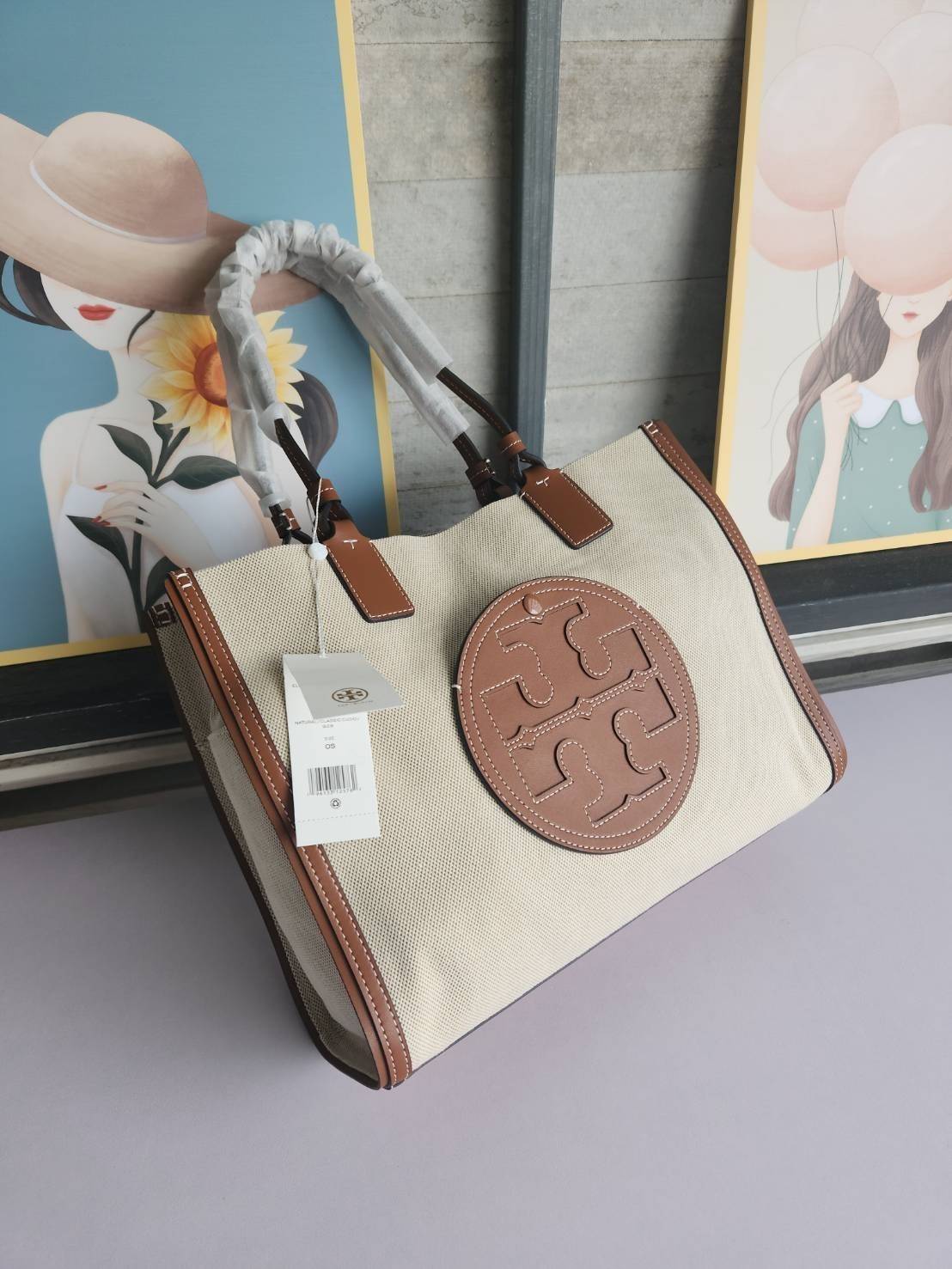 TORY BURCH ELLA CANVAS TOTE BAG กระเป๋าโท้ตน้ำหนักเบาของเราพร้อมป้ายโลโก้ Ella ทำจากผ้าใบที่ทนทานพร้อมรายละเอียดหนังและกระเป๋าด้านใน อเนกประสงค์ ทรงคลาสสิก และสร้างขึ้นอย่างสวยงามด้วยฝีมือช่างฝีมือ สายรัดแคบช่วยให้วางราบกับไหล่ได้อย่างสบาย เหมาะสำหรับทุกว