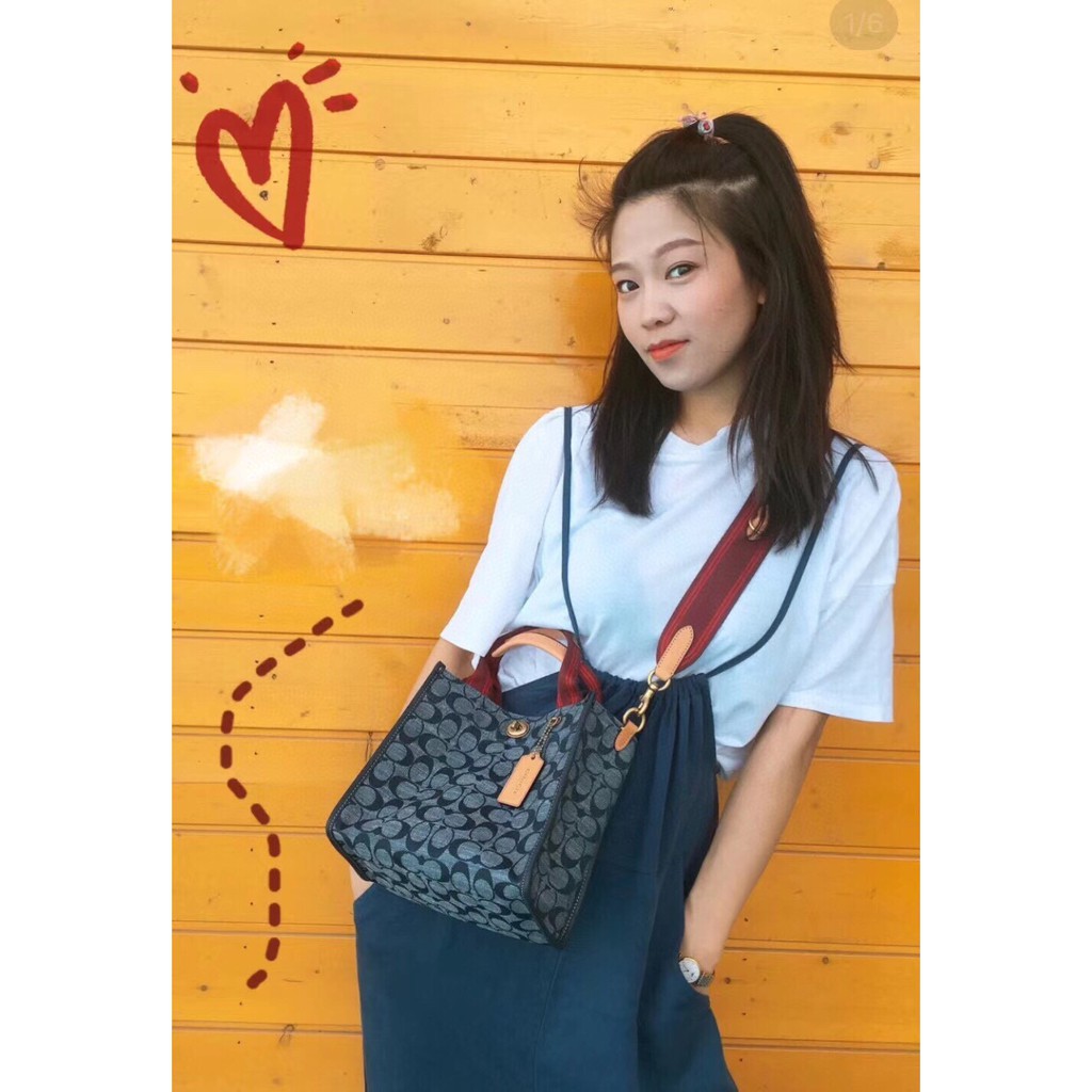 COACH Tote 34 In Signature Chambray หากคุณกำลังมองหากระเป๋าที่มีดีไซน์แปลกตา ไม่ค่อยเหมือนที่พบเห็นทั่วไป ต้องเป็นรุ่นนี้เลยค่ะ นอกจากจะผลิตจากผ้าแชมเบรย์ซึ่งมีน้ำหนักเบาแล้ว ยังให้สีสันคล้ายกับสียีนส์ สายสะพายและหูหิ้วสไตล์สปอร์ต ที่สำคัญยังมีหมุดปิดกระเ