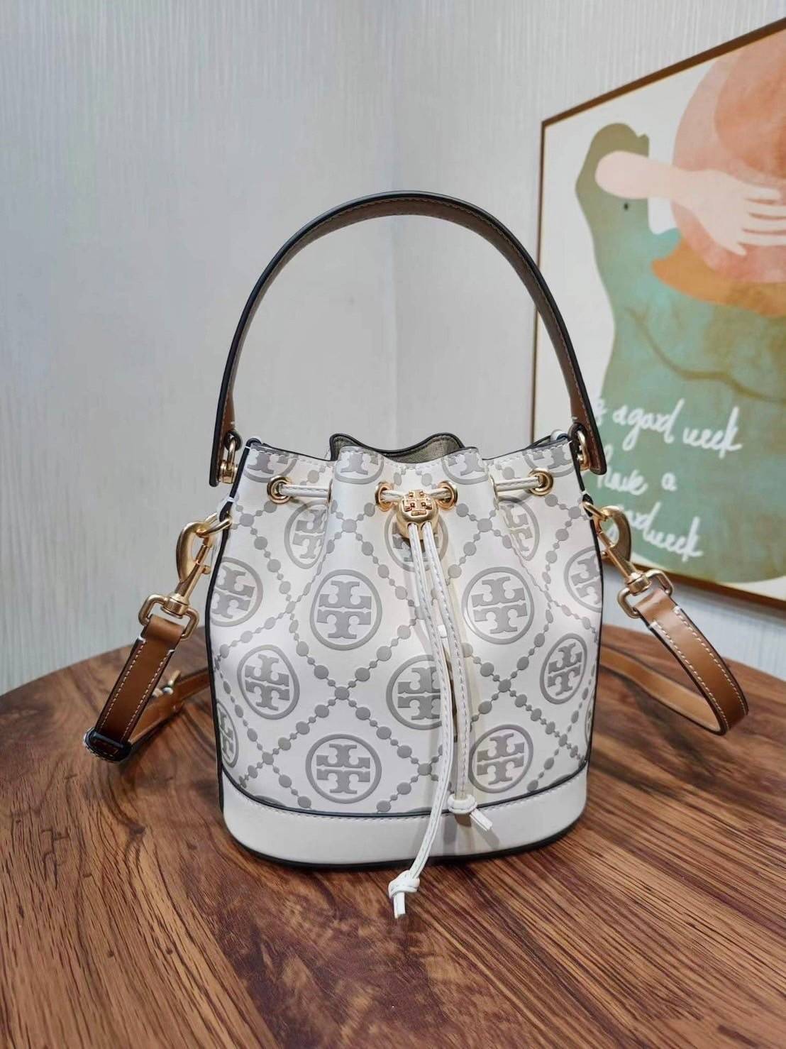 Medium : Tory Burch T Monogram Embossed Bucket Bag กระเป๋าถือหรือสะพายไหล่ ประดับด้วยลวดลายอันเป็นสัญลักษณ์ของแบรนด์ ถูกประดิษขึ้นด้วยความพิถีพิถันวัสดุหนังอย่างดี ด้านในบุด้วยหนังไมโครซูแอคเนื้อนุ่มทำความสะอาดง่าย กระเป๋าผ่าหลังด้านนอก1ช่อง ด้านใน 1ช่อง 
