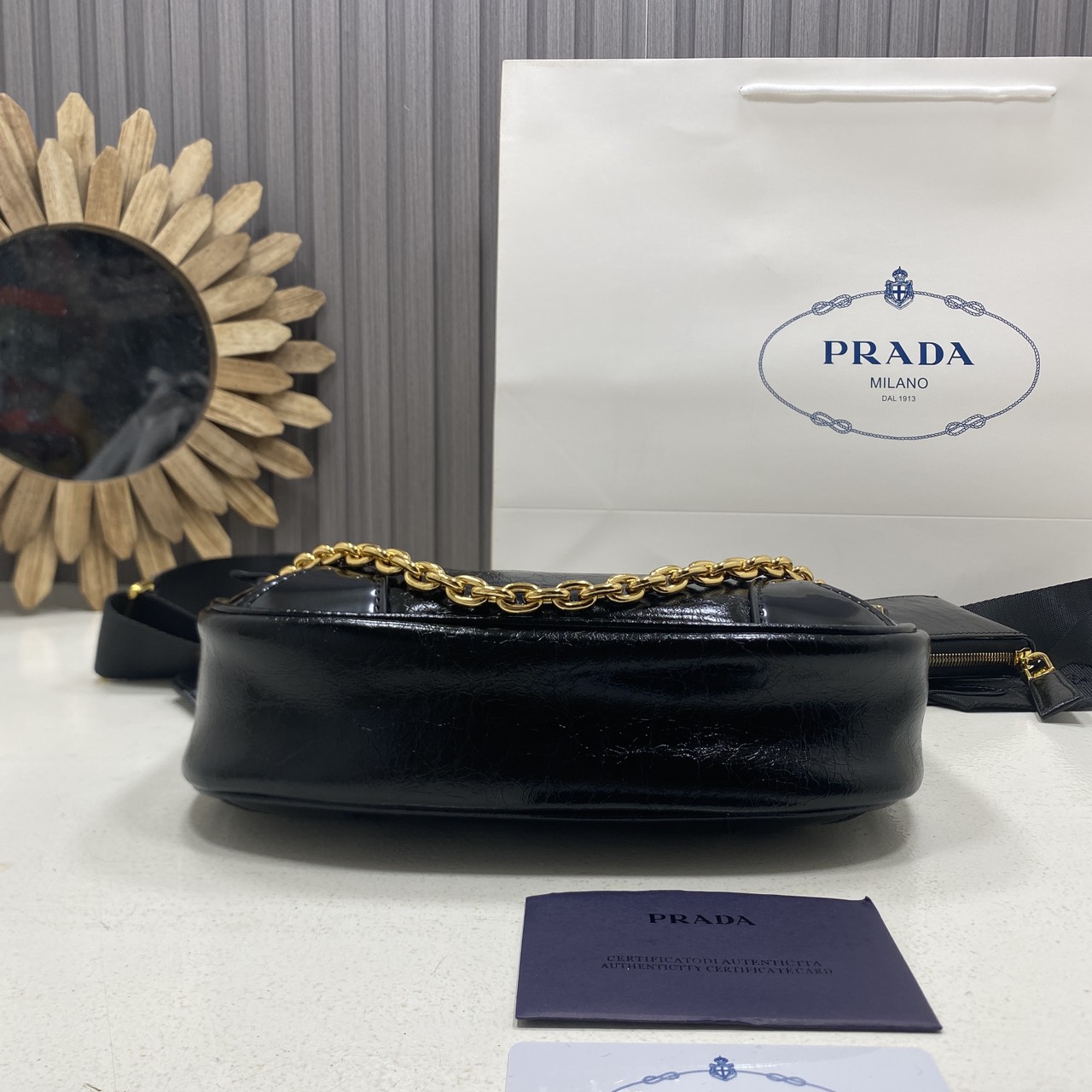 ORI หนังแท้ | Prada Re-Edition 2005 bag in Naplak leather กระเป๋าสะพายทรงโฮโบหนังแก้ว ดีไซน์เอฟเฟกต์มันวาวและเท็กซ์เจอร์ที่มีเสน่ห์สไตล์วินเทจ พร้อมทริกห้อยเพิ่มสไตล์สัมผัสที่โดดเด่นและร่วมสมัยยิ่งขึ้น