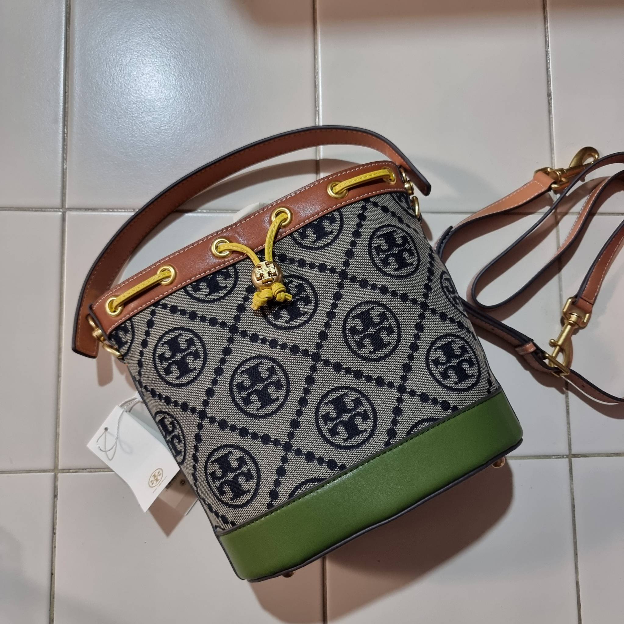 TORY BURCH T MONOGRAM COLORBLOCK JACQUARD BUCKET BAG ไอเท็มใหม่ที่ใครๆก็รอ กระเป๋าบัคเก็ตทรงสวย ที่ยังคงให้ความโดดเด่นด้วยลวดลายเอกลักษณ์ เพิ่มเติมดีไซน์บล็อคสี ตัดกันได้อย่างลงตัว ถักทอบนวัสดุ woven jacquard ลายคมชัด สลับส่วนของหนังแท้ ภายในเป็นช่องโล่งก