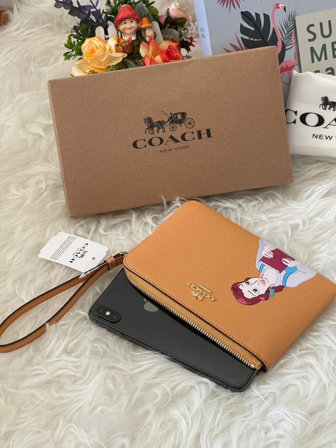 Coach & Disney Corner Zip Wristlet เปิดตัวคอลเลคชั่นเมื่อความดาร์กและโรแมนติกโคจรมาพบกัน เมื่อแบรนด์เครื่องหนังสัญชาติอเมริกัน Coach ร่วมมือกับ Disney สร้างสรรค์คอลเล็กชั่นพิเศษที่ได้รับแรงบันดาลใจมาจากเทพนิยายอเมริกันโกธิกของนิวยอร์ค ถ่ายทอดผ่านเหล่าตัวล