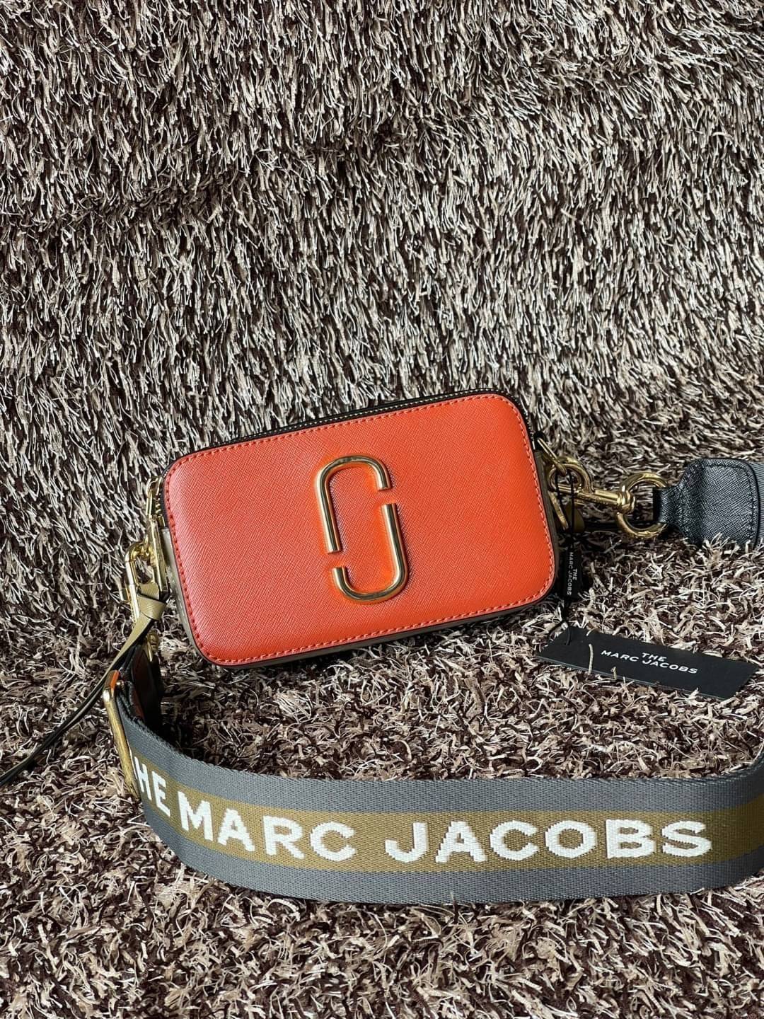 Marc Jacobs Snapshot Bag กระเป๋าแบรนด์ดังจากสัญชาติอเมริกัน นับได้ว่ารุ่นนี้เป็นรุ่นทรงฮิตเลยทีเดียว โดยด้านหน้ากระเป๋าจะเป็นโลโก้แบบโลหะที่เป็นสัญลักษณ์ของแบรนด์นี้ มาพร้อมสายสะพายที่จะสะพายยังไงก็ดูโดดเด่น เพราะขนาดใหญ่ที่สกรีนตัวอักษรโลโก้ ในรูปแบบต่าง