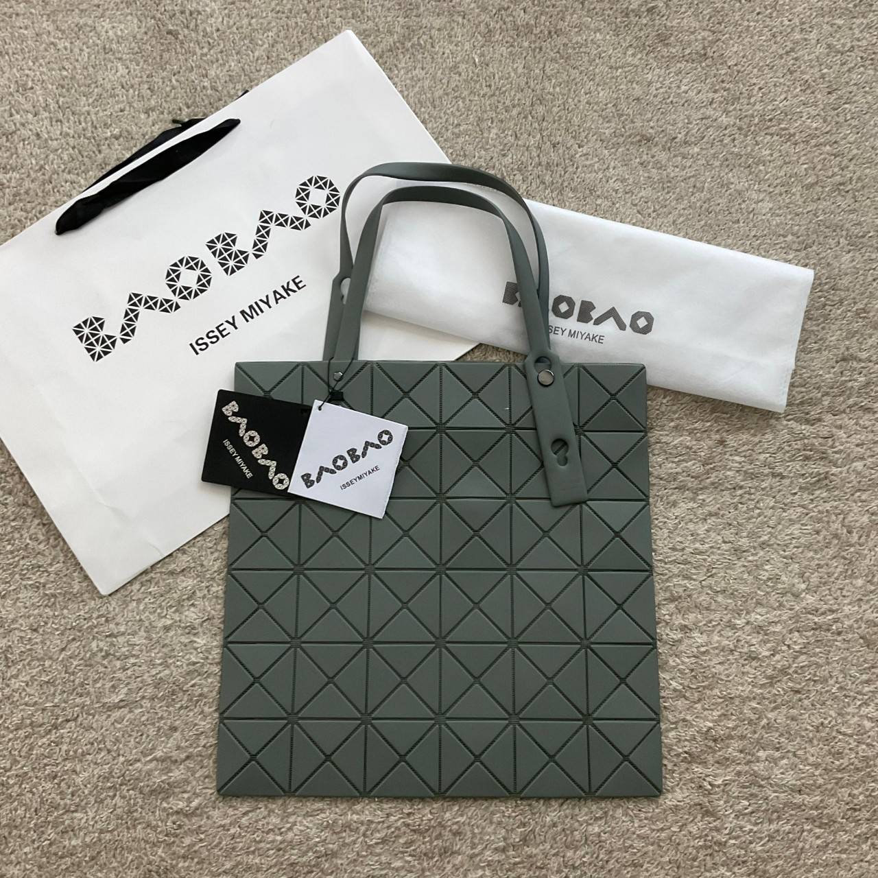 BAO BAO ISSEY MIYAKE LUCENT ONE-TONE กระเป๋าสะพายไหล่ ทรงโท้ท ใบใหญ่สวยมาก ปรับได้หลายทรงตามเอกลักษณ์เฉพาะของแบรนด์นี้ วัสดุ 100% POLYESTER PARTLY: SYMYHETIC LEATHER ด้านในใส่ของได้เยอะมาก ใส่ไอแพด สมุดโน้ตได้สบายเลย วัยทำงานหรือวัยนักศึกษา อย่างน้อยต้องม