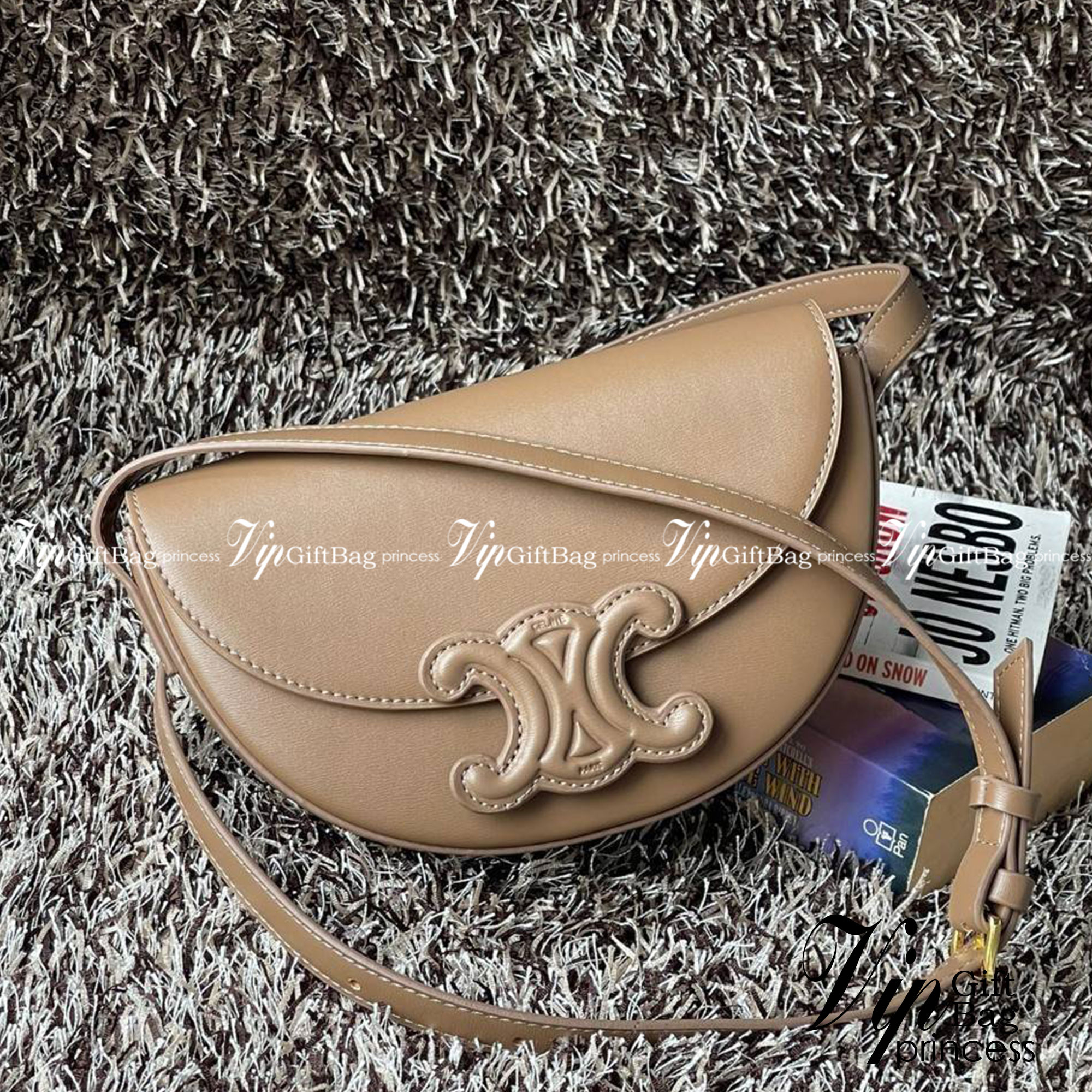 CELINE BESACE CUIR TRIOMPHE IN SMOOTH กระเป๋ารุ่นนี้นำเสนอในรูปทรงฮาล์ฟมูนที่ตอนนี้กำลังงมาแรง เปิดด้วยกระดุมแป๊กเพื่อเผยให้เห็นช่องภายในที่กว้างขวางและกระเป๋าด้านในแบบแบน คุณสมบัติที่โดดเด่นอีกอย่างของกระเป๋าอยู่ที่โลโก้ขนาดใหญ่ รูปทรงสะดุดตา สามารถสะพาย