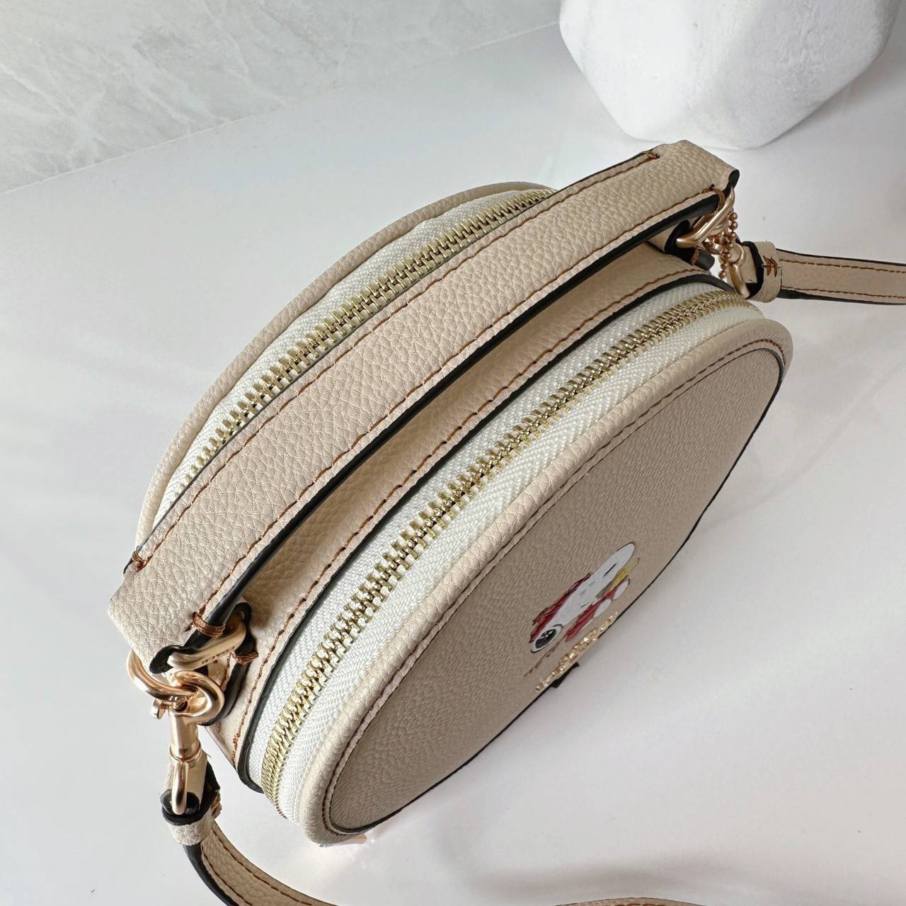 COACH X PEANUTS CANTEEN CROSSBODY WITH SNOOPY PRESENT MOTIF (CE845,CF290) กระเป๋าสะพายข้างทรงกลมไซส์มินิ มีหูจับ วัสหนังแท้ ด้านหน้าโดดเด่นด้วยรูปการ์ตูนSnoopy