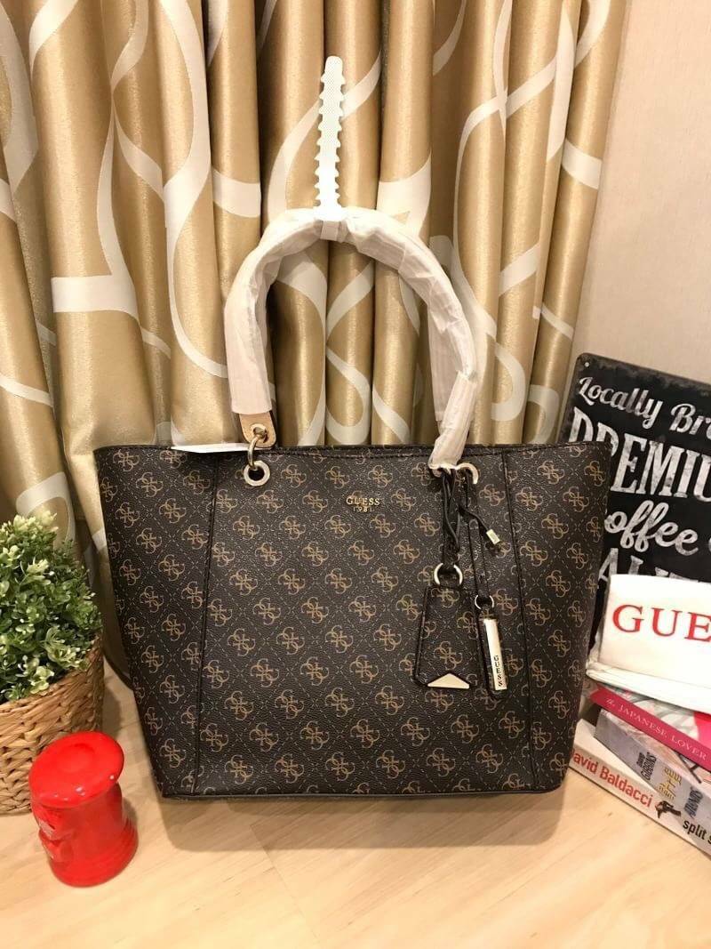 GUESS Kamryn Q Logo Tote สไตล์คลาสสิค ฐานกว้างตั้งอยู่ทรง วัสดุหนังpuลายsignature แบรนด์รอบใบ เปิดปิดด้วยซิปเดียวด้านบน ใช้งานง่าย บุด้วยผ้าสกรียโลโก้ มีช่องเล็กและช่องซิปแยกใช้งานเป็นสัดส่วน ประดับtagโลหะหุ้มหนังเป็นดีเทล ใบใหญ่ใส่นิตยสาร และของใช้ประจำว
