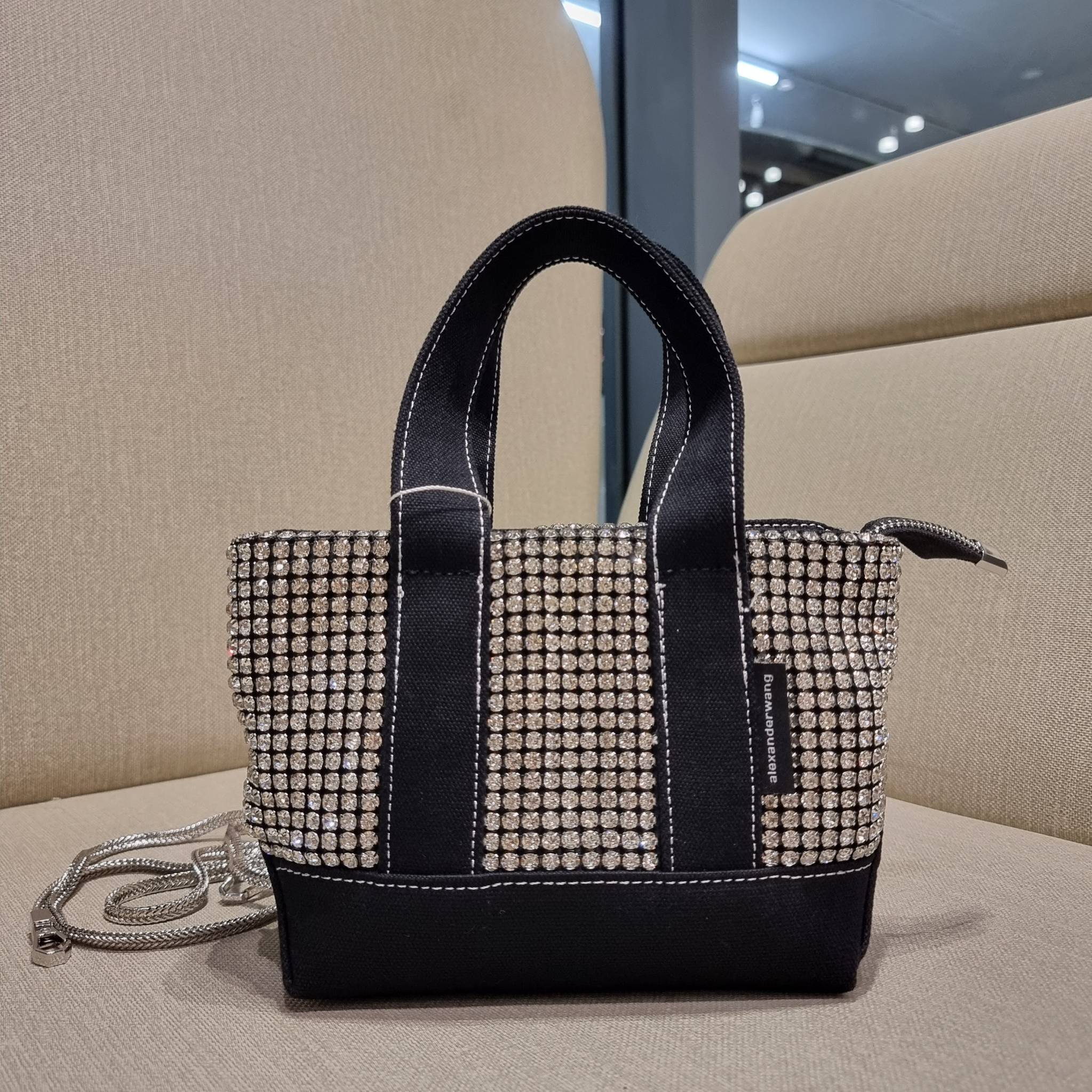ALEXANDER WANG HANDBAG MINI TOTE WITH RHINESTONE กระเป๋าทรงมินิโท้ท น่ารักน่าเอ็นดู น่าใช้เหลือเกิน!! ด้วยความโดดเด่นเด่นของการตกแต่งพลอยเทียม ให้ดีเทลหรู ตัดสลับด้วยผ้าแคนวาส เพิ่มความทนทาน ลงตัวมากๆ และยังใช้งานง่ายด้วยหูจับในตัว เปิด-ปิดด้วยซิป ภายในเป