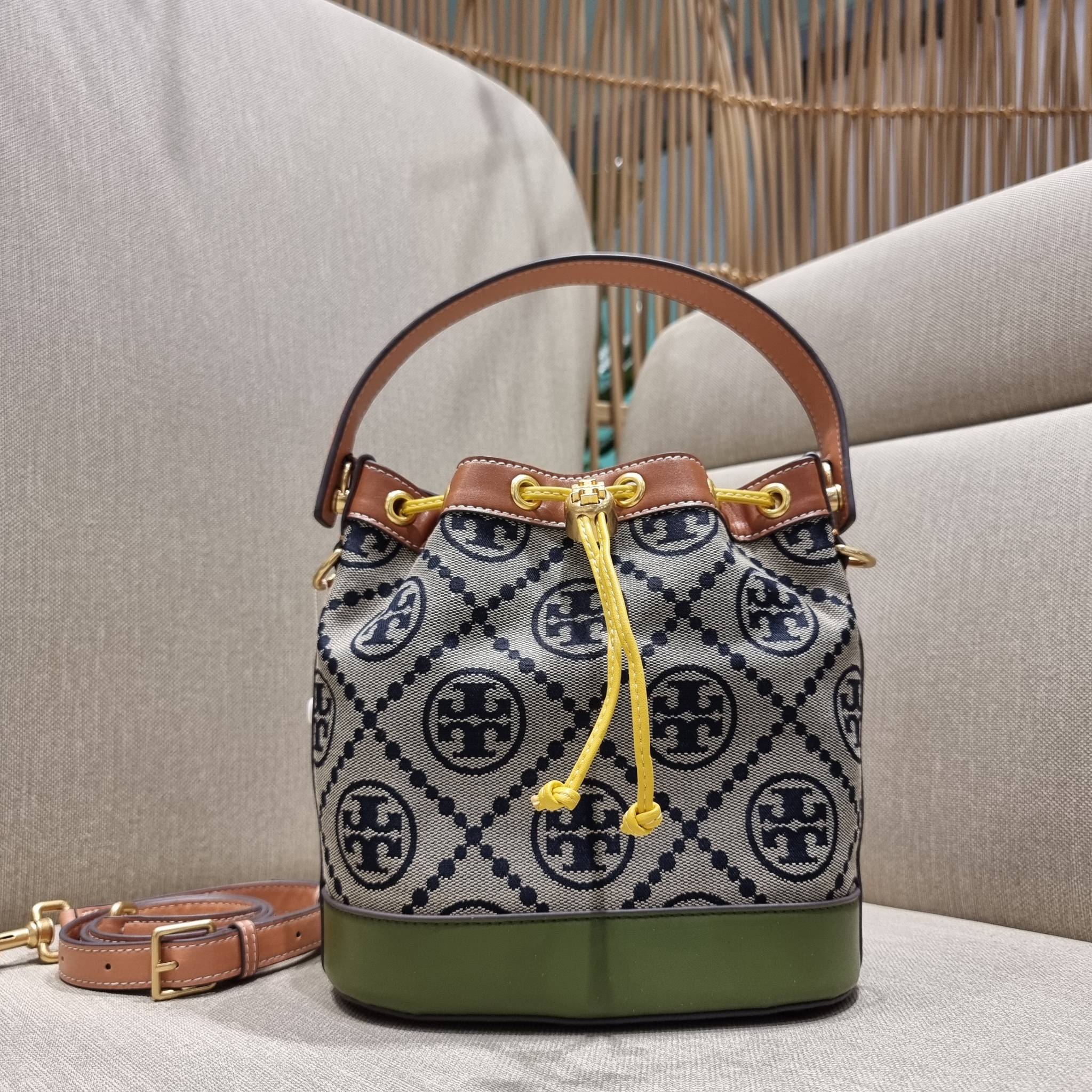 TORY BURCH T MONOGRAM COLORBLOCK JACQUARD BUCKET BAG ไอเท็มใหม่ที่ใครๆก็รอ กระเป๋าบัคเก็ตทรงสวย ที่ยังคงให้ความโดดเด่นด้วยลวดลายเอกลักษณ์ เพิ่มเติมดีไซน์บล็อคสี ตัดกันได้อย่างลงตัว ถักทอบนวัสดุ woven jacquard ลายคมชัด สลับส่วนของหนังแท้ ภายในเป็นช่องโล่งก