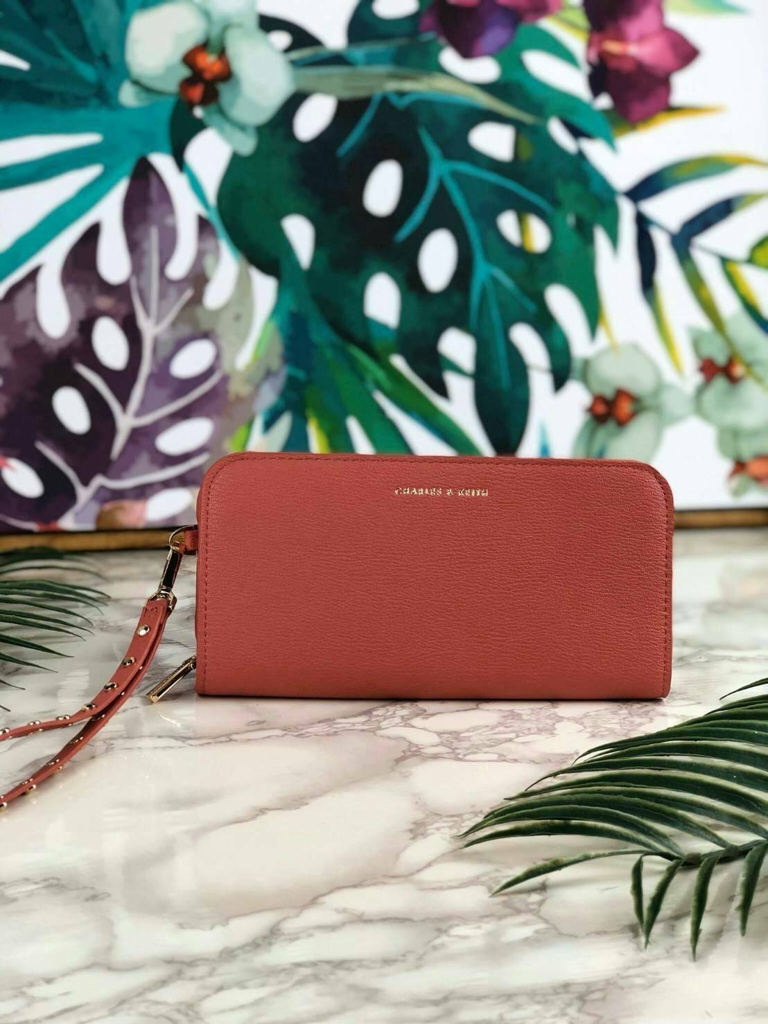 CHARLES & KEITH CLASSIC ZIP AROUND WALLET กระเป๋าเงินใบยาวซิปรอบ มีสายคล้องมีสีเข้ากระเป๋า 1 เส้น ใช้งานง่ายมากๆ คล้องมือก็เก๋ ด้านหน้าปั๊มโลโก้แบรนด์ เปิดปิดด้วยซิปรอบ ที่สายคล้องมือแต่งหมุดสีสวยเด่น ถอดสายได้ จุบัตรได้ 12 ใบ มีช่องซิปใส่เหรียญและช่องใส่