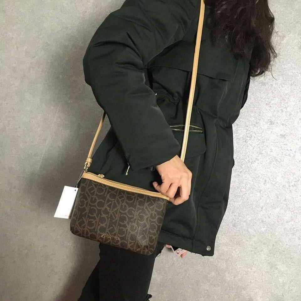 Calvin Klein Cross Body Bag กระเป๋าสะพายรุ่นใหม่ล่าสุดหนังสวย สกรีนลาย Signature แบรนด์รอบใบ ประดับโลโก้แบรนด์ สีทองด้านหน้า เปิดปิดด้วยซิป น้ำหนักเบา ภายใน โล่งกว้าง มีช่องใส่บัตร และช่องซิป ใส่ iphone+ ได้ มาพร้อมสายสะพายยาว ขนาดกำลังน่ารัก สะพายคล่องตั