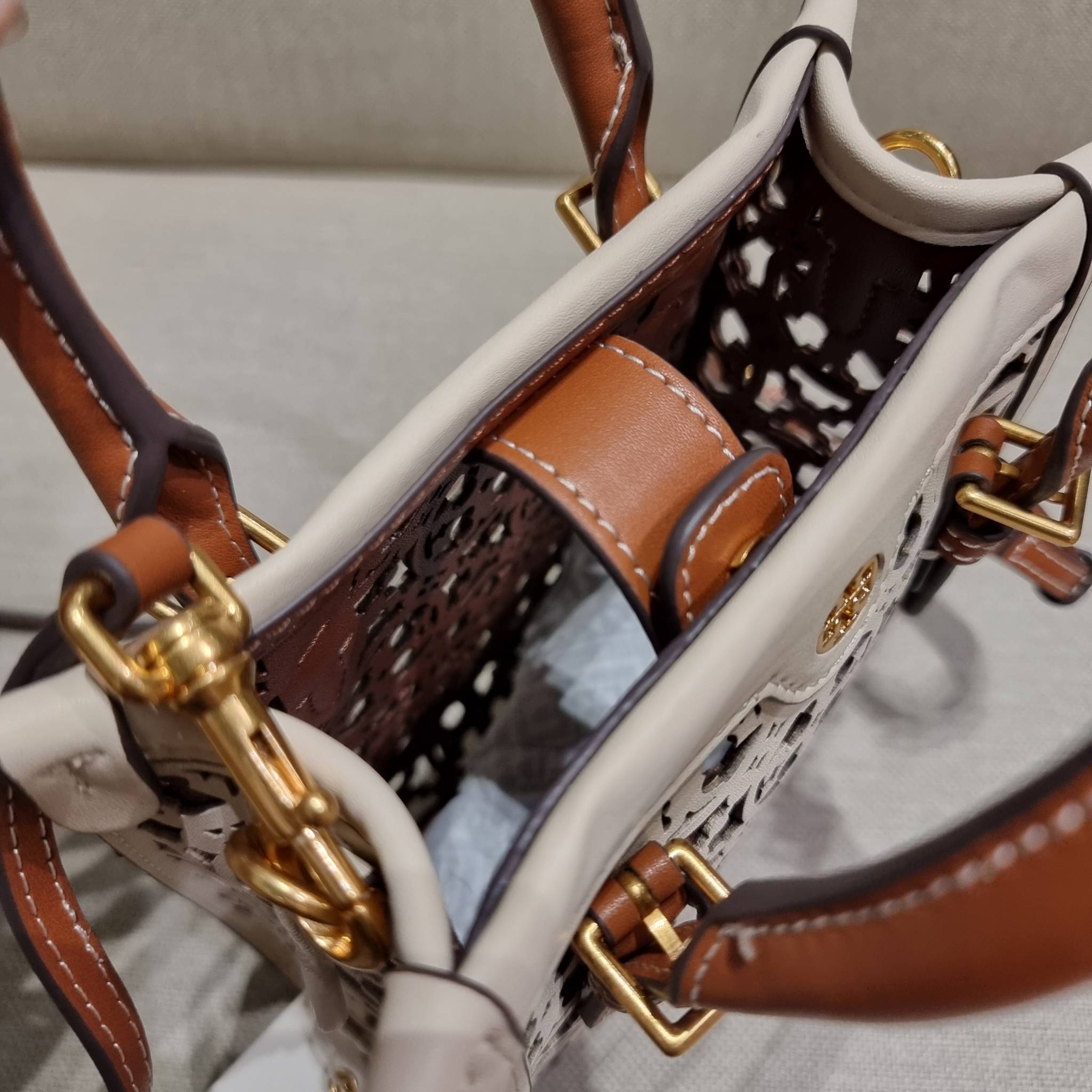 TORY BURCH T MONOGRAM LASER-CUT MINI TOTE ใจบางที่สุดกับคอลเลคชั่นนี้ กับกระเป๋าสะพายทรงโท้ท ไซส์มินิ ที่เพิ่มดีเทลความแพงด้วยการฉลุลวดลายโมโนแกรมรอบใบ ถักทอเป็นเส้นลายสานที่สวยงามมาก งานฝีมือจริงๆ วัสดุหนัง cowhide ปากกระเป๋ามีแถบแม่เหล็กกันหล่น และมีหูจ