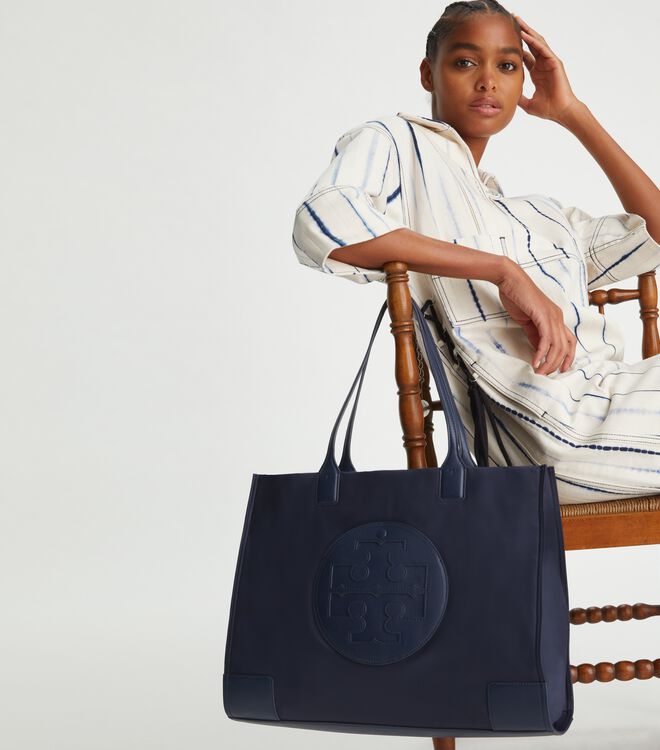 กระเป๋าทรงโท้ทใบใหญ่ TORY BURCH ELLA TOTE BAG วัสดุ NYLON ทั้งใบตัดด้วยหนังสีดำ แต่งโลโก้แบรนด์ด้านหน้า ด้านข้างมีกระดุม สามารถขยายทรงได้ ด้านในเปิดปิดด้วยกระดุมแม่เหล็กฝัง ช่องกว้างหลักหนึ่งช่องและช่องซิปอีกช่อง สามารถใส่แล็ปท็อปได้สบาย ใบใหญ่เว่อวัง ไอเ