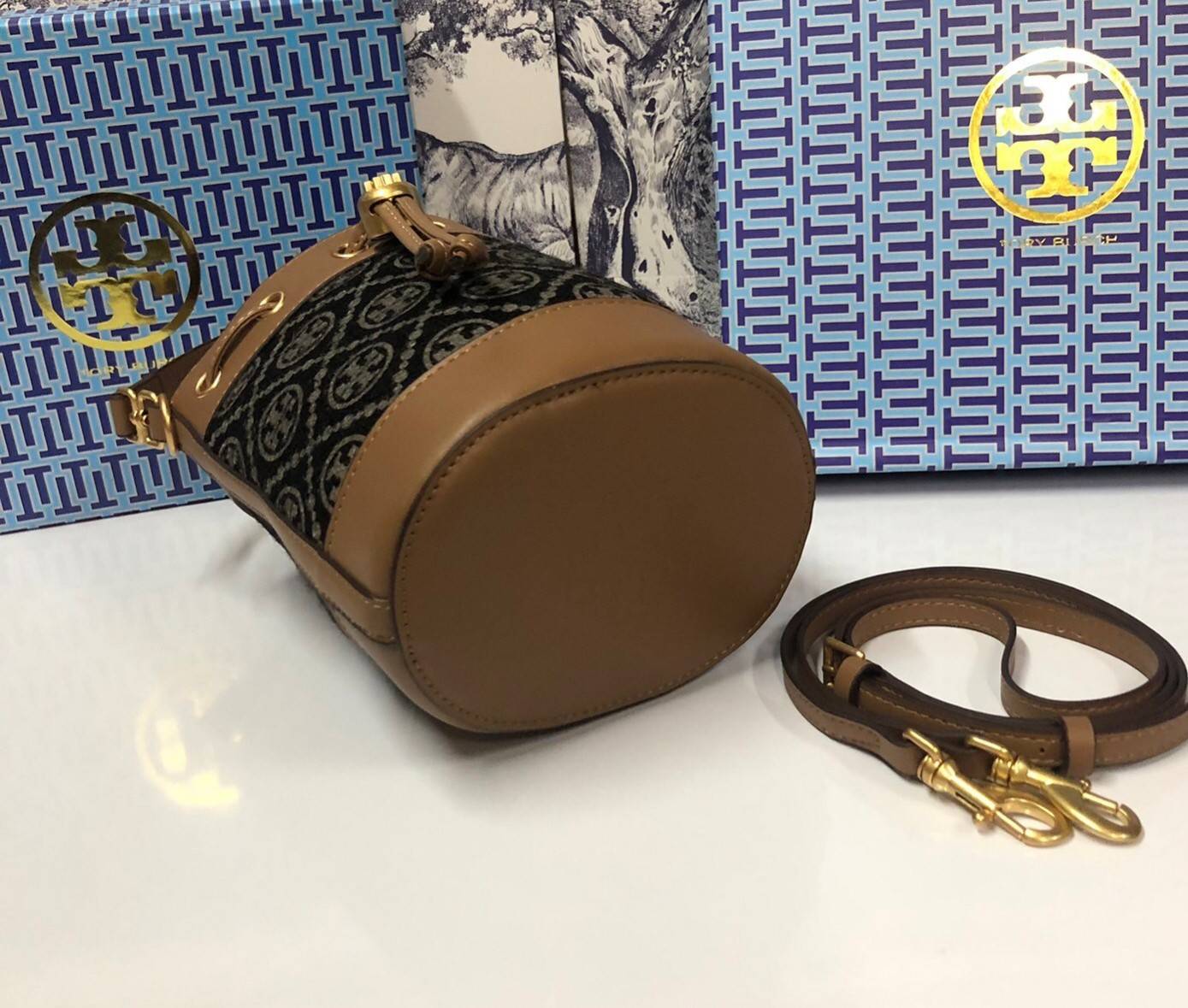 Mini : Tory Burch T Monogram Chenille Bucket Bag เปิดตัวอีกหนึ่งรุ่นกับกระเป๋าลาย T MONOGRAM รุ่นใหม่ล่าสุดจาก TORY BURCH พลาดไม่ได้กับโลโก้สุดคลาสสิก ลวดลาย T Monogram คือวัสดุ chenille หรือที่เรียกว่า ด้านไหมกำมะหยี่ มารังสรรค์ลงบนกระเป๋าBucketใบนี้ เป็