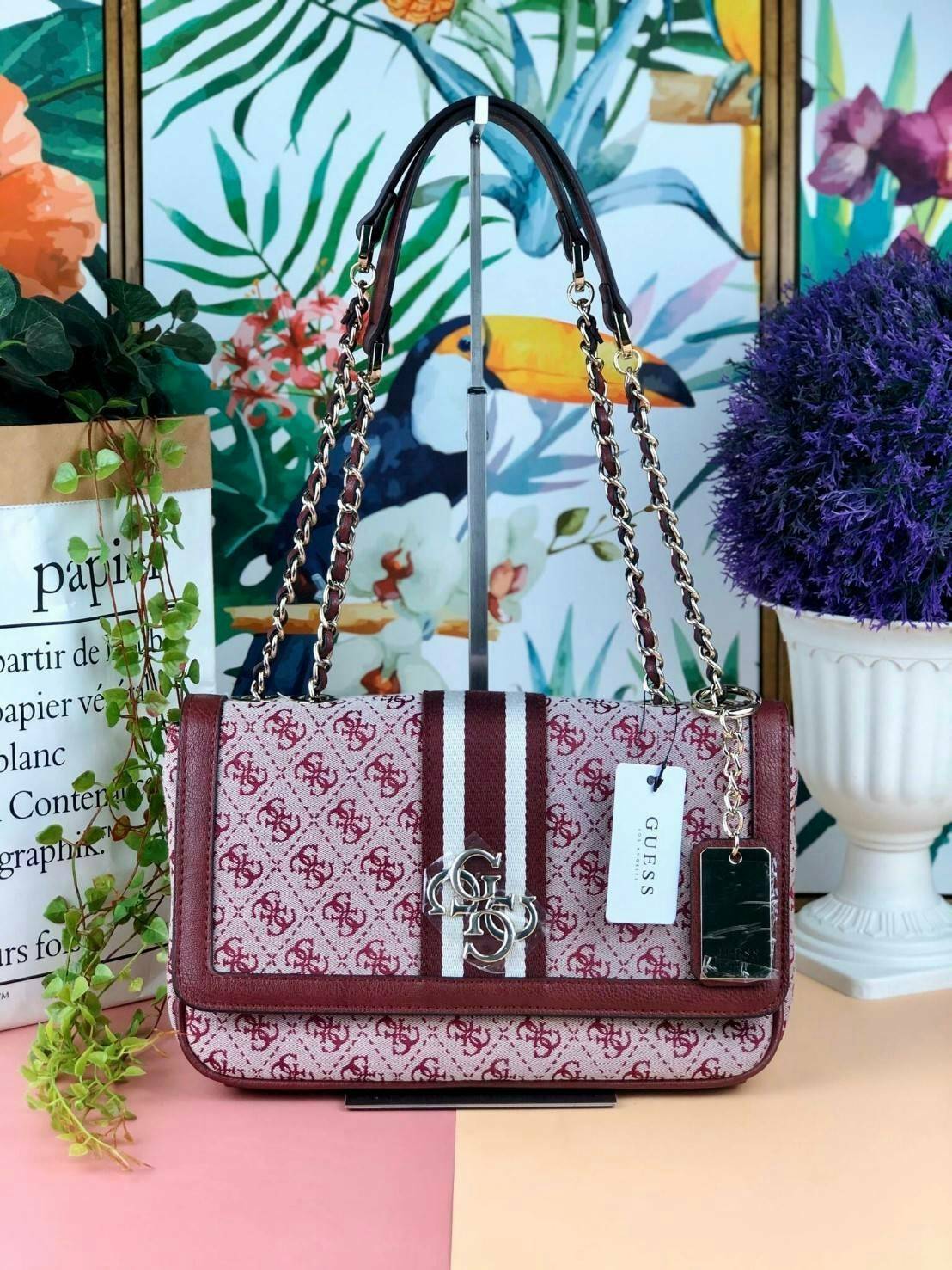 Guess Logo city handbag กระเป๋าสะพายไหล่ ตัวกระเป๋าเป็นผ้าลาย signature ของแบรนด์ ตัดกับหนังที่ตัวขอบกระเป๋า มาพร้อมพวงกุญแจโลโก้แบรนด์ ด้านหน้ามีโลโก้แบรนด์ ด้านหลังมีช่องใส่โทรศัพท์/บัตรได้ เปิดปิดแบบกระดุมแม่เหล็กซ้าย-ขวา ด้านในมีช่องซิป เล็ก 1 ช่อง แล