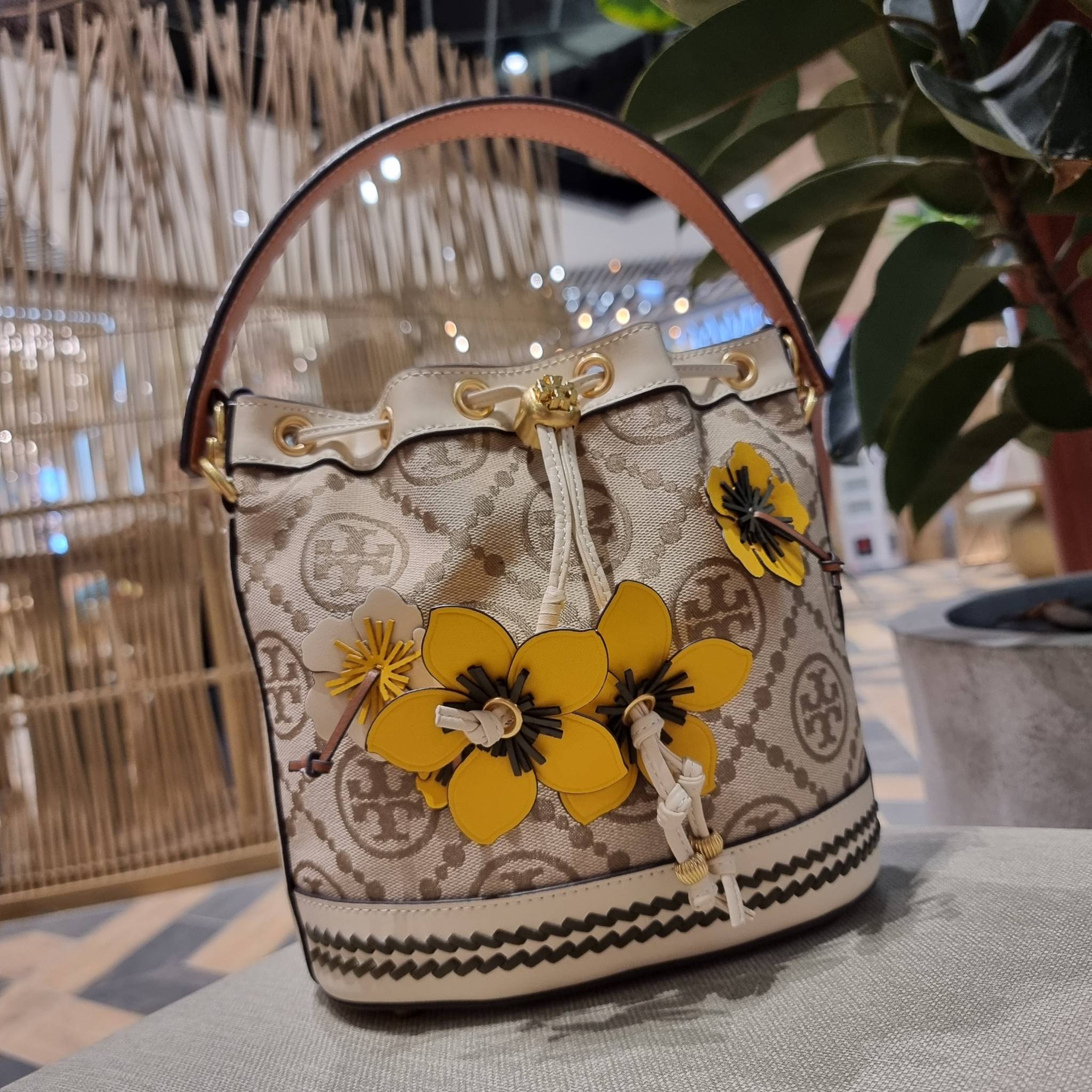 TORY BURCH T MONOGRAM FLORAL BUCKET BAG คอลเลคชั่นใหม่ พร้อมเสิร์ฟความสวยให้ถึงบ้าน!! กระเป๋าบัคเก็ตทรงยอดนิยม ดีไซน์ใหม่ล่าสุด สไตล์งานคราฟ มีลูกเล่นประดับดอกไม้กับตัวกระเป๋า และตัวรูดสาย วัสดุผ้า jacquard ตัดสลับหนังแท้ หูจับและขอบกระเป๋าตกแต่งลายสานสวย