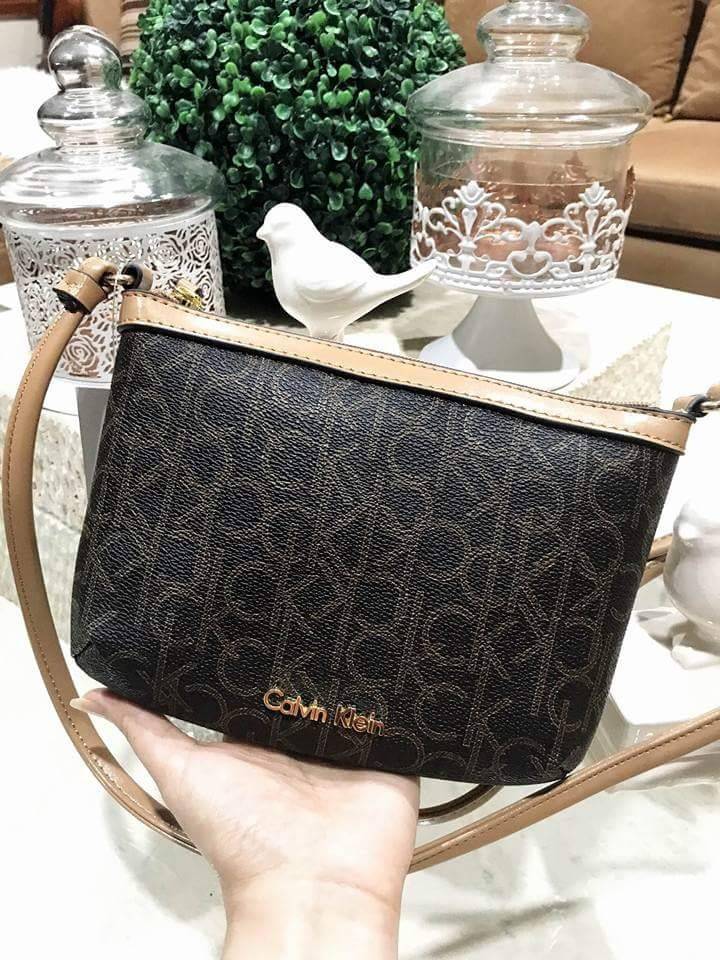 Calvin Klein Cross Body Bag กระเป๋าสะพายรุ่นใหม่ล่าสุดหนังสวย สกรีนลาย Signature แบรนด์รอบใบ ประดับโลโก้แบรนด์ สีทองด้านหน้า เปิดปิดด้วยซิป น้ำหนักเบา ภายใน โล่งกว้าง มีช่องใส่บัตร และช่องซิป ใส่ iphone+ ได้ มาพร้อมสายสะพายยาว ขนาดกำลังน่ารัก สะพายคล่องตั