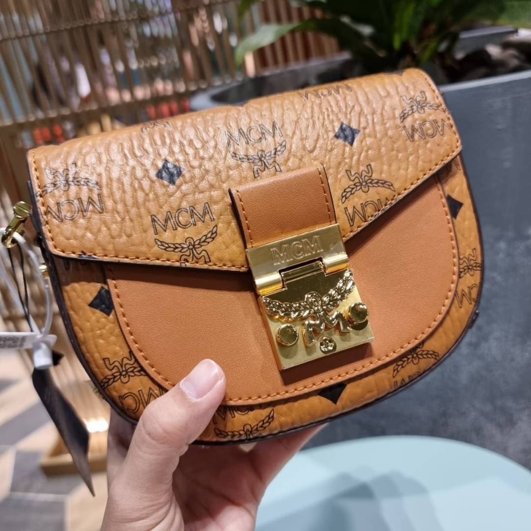 M.C.M MINI PATRICIA CROSSBODY IN VISETOS กระเป๋าสะพายไซส์มินิ แรงดีไม่มีตกน้า คอลเลคชั่นนี้ดีไซน์แปลกใหม่ ทรงโค้งมน สวยหรู ด้านข้างตกแต่งหมุดทองรอบใบ วัสดุตัวกระเป๋าเป็นหนังแคนวาสคุณภาพดี ภายในเป็นหนังกลับสีส้มโดดเด่นเป็นเอกลักษณ์ มีช่องใส่บัตรแยกให้ เปิด