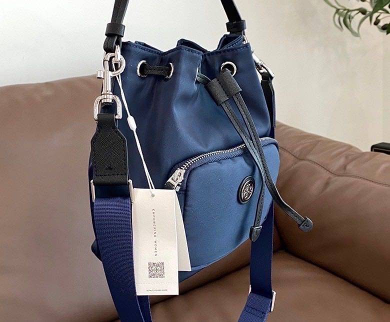 Tory Burch Virginia Nylon Bucket Bag / Tory Burch logo-plaque bucket bag กระเป๋าสะพายทรงบัคเก็ต เปิด-ปิดหนังรูดปากกระเป๋า มีหูหิ้วในตัว คล้องแขนเก๋ๆ ภายในเป็นช่องโล่ง มีช่องย่อย ใส่ของสำคัญจุกจิกได้ มีสายครอส จะสะพายไปไหนก็ได้ทุกโอกาส สวยเลิศทุกสี พร้อมส่