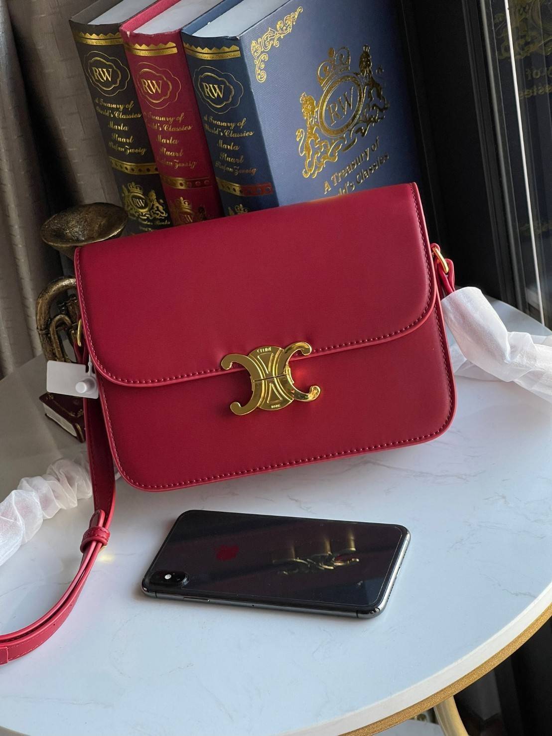 Celine MEDIUM TRIOMPHE BAG IN SHINY มีรูปทรงเป็นกล่องคล้ายกับกระเป๋า Classic Box แต่มีการออกแบบโลโก้ที่สะดุดตาแบบวินเทจ ด้วยดีไซน์ที่ดูโฉบเฉี่ยว แต่คงความคลาสสิคอย่างเต็มเปี่ยม ทำให้เป็นที่ดึงดูดความสนใจของสาวๆ สายสะพายสามารถปรับระดับได้ มีความคล่องตัวในก