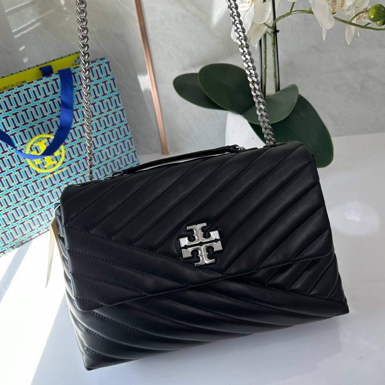 TORY BURCH KIRA CHEVRON CONVERTIBLE SHOULDER BAG กระเป๋าสะพายไซส์ใหญ่ หรูหราสุดคลาสสิก วัสดุหนังแกะทั้งใบ เปิด-ปิดด้วยกระดุมแม่เหล็ก ภายในเป็นช่องโล่ง ใส่ของสำคัญได้ครบ สายสะพายในตัวปรับได้ 2 แบบ สะพายไหล่โซ่คู่หรือจะ ครอสบอดี้ก็เริ่ดคะ