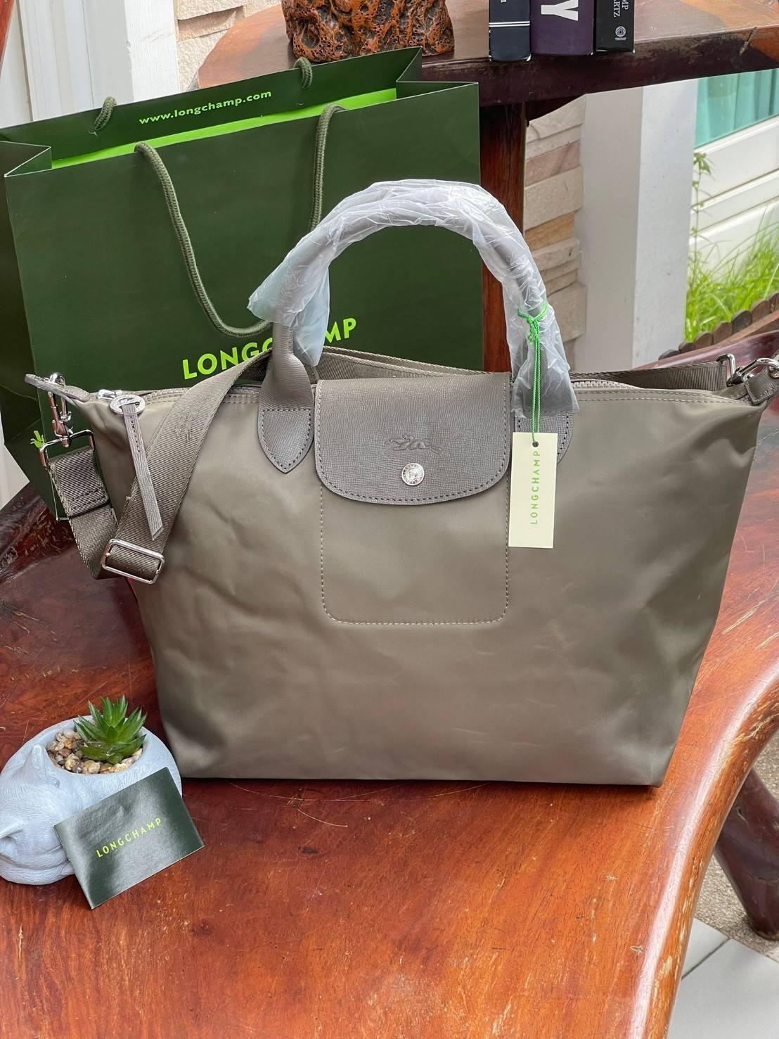 Longchamp LE PLIAGE NÉO TOP HANDLE BAG อีกหนึ่งรุ่นยอดนิยม ที่สาวๆ ต้องมีไว้เก็บไว้สักใบ กระเป๋าโท้ทใบนี้ มาพร้อมกับสีที่มีสไตล์เรียบง่าย มีสายสะพายยาวปรับสั้นยาวได้ช่วยให้คุณสามารถสะพายไหล่ได้อย่างสบาย ในตัวสายปักโลโก้อันเป็นสัญลักษณ์ ในขณะที่ที่ปิดแบบซิ