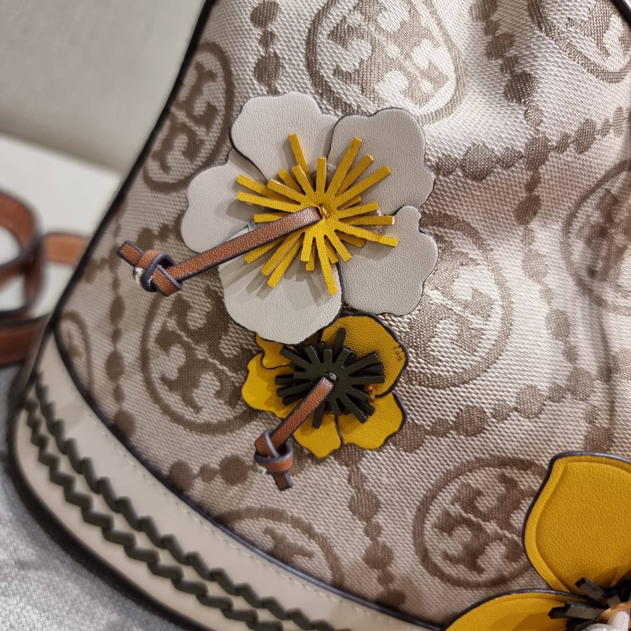 TORY BURCH T MONOGRAM FLORAL BUCKET BAG คอลเลคชั่นใหม่ พร้อมเสิร์ฟความสวยให้ถึงบ้าน!! กระเป๋าบัคเก็ตทรงยอดนิยม ดีไซน์ใหม่ล่าสุด สไตล์งานคราฟ มีลูกเล่นประดับดอกไม้กับตัวกระเป๋า และตัวรูดสาย วัสดุผ้า jacquard ตัดสลับหนังแท้ หูจับและขอบกระเป๋าตกแต่งลายสานสวย