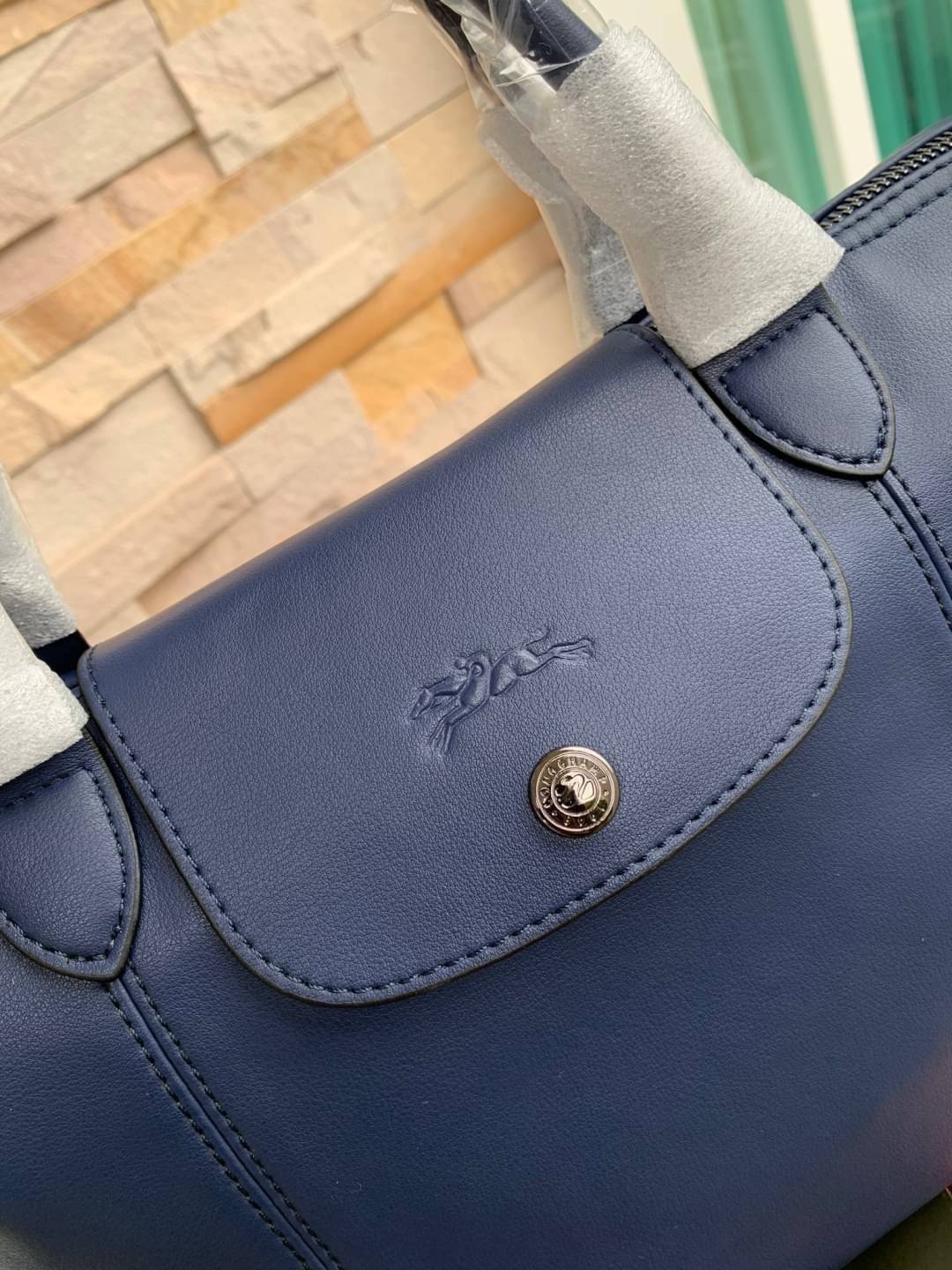 Longchamp LE PLIAGE CUIR TOP HANDLE BAG S เรียกว่าเป็นกระเป๋าอีกหนึ่งรุ่นที่ไม่ว่ายังไงก็ฮอตฮิตและติดเทรนด์ตลอดไม่เคยเปลี่ยนกับ ทรง Le Pliage Cuir หนึ่งในตระกูลกระเป๋าสุดไอคอนิกจากแบรนด์ เมื่อรุ่น Le Pliage Cuir ในรูปแบบของหนังแกะ Metis ได้ถือกำเนิดขึ้นใน