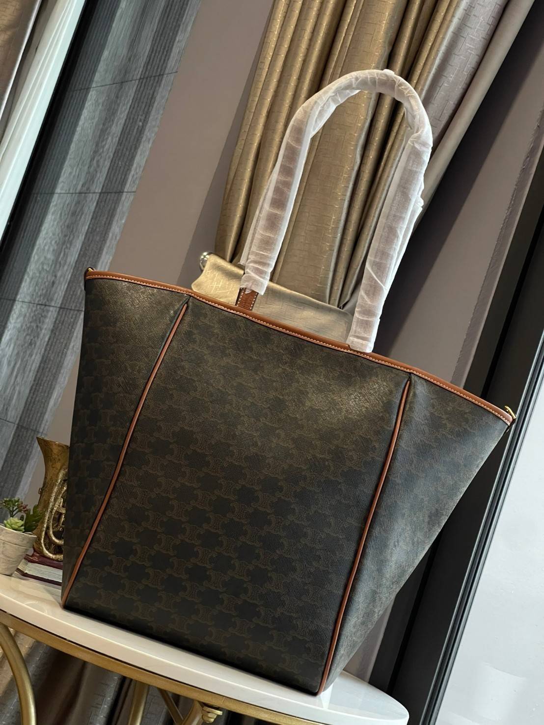 Celine Medium shopping bag in Triomphe canvas มาในรูปแบบ กระเป๋า Shopping Bag ใบสวยสง่า เป็นกระเป๋าดีไซน์เรียบง่าย แมตช์ได้กับทุกชุด ผลิตจากผ้าแคนวาสชนิดพิเศษซึ่งโดดเด่นด้วยลายเอกลักษณ์ของ Triompe เป็นใบที่เหมาะกับการใช้ประจำวันเป็นอย่างมาก ด้วยรูปทรงสี่เ