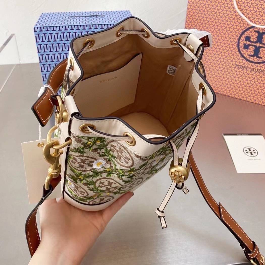 TORY BURCH T MONOGRAM JACQUARD EMBROIDERED BUCKET BAG ครั้งแรกกับโมโนแกรม ที่ได้รับแรงบันดาลใจมาจากโลโก้สุดคลาสสิก กลับมาอีกครั้งในรูปแบบของ ลวดลาย T Monogram ที่ผสมผสานความร่วมสมัยเข้ากับความเป็นเอกลักษณ์ของแบรนด์เข้าไว้ด้วยกัน โดยเป็นการนำเอาลวดลาย T Mo