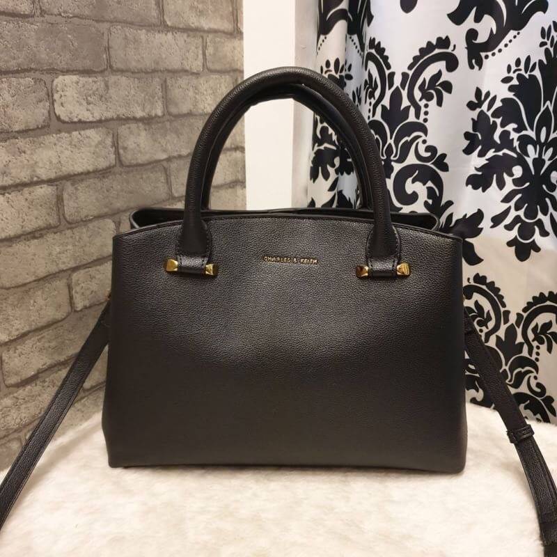 CHARLES & KEITH CLASSIC TOP HANDLE BAG กระเป๋าถือหรือสะพายใบใหญ่ ทรงแข็ง หนัง pu สวย ดีไซน์เรียบหรู ดูดี ด้านหน้าป้ายโลโก้แบบนูน ด้านหลังมีซ่องซิป 1 ช่อง เปิด-ปิดแบบกระดุมแม่เหล็ก ภายในมี 2 ช่องใหญ่ คั่นกลางด้วยช่องซิป มีหมุดรองรองฐานสี่มุม มาพร้อมสายสะพา