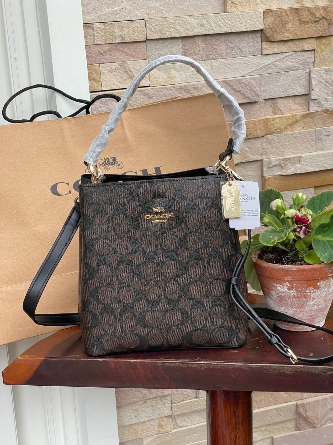 COACH SMALL TOWN BUCKET BAG IN SIGNATURE สำหรับสาวแฟชั่นที่ชอบรายละเอียดชิคๆ ดีไซน์สุดเก๋ แนะนำเลยสำหรับกระเป๋าทรงบักเก็ตใบนี้ เชื่อว่าสาว ๆ หลายคนชื่นชอบ เป็นไอเทมที่สามารถแมทช์ได้กับเสื้อหลากหลายสไตล์ บรรจุของได้เยอะโดยที่กระเป๋าไม่เสียทรง แบ่งช่องใช้งา