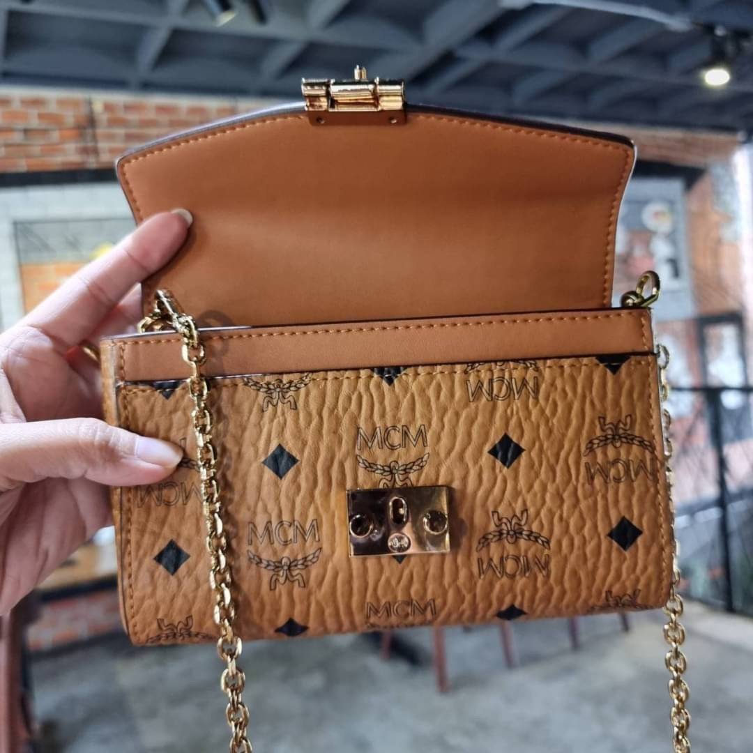 M.C.M SMALL MILLIE FLAP CROSSBODY IN VISETOS ไซส์ใหม่พกพาสะดวก!! กระเป๋าสะพายกึ่งคลัทช์ รอบนี้มาไซส์สวย สามารถใช้แทนกระเป๋าสตางค์ได้เลย ใส่โทรศัพท์มือถือได้ทุกรุ่น ใส่ของสำคัญสบายๆ มาพร้อมสายสะพายโซ่สีทองหรูหรา รูปทรงดีไซน์ร่วมสมัย ใช้งานง่ายด้วยตัวล็อค ว