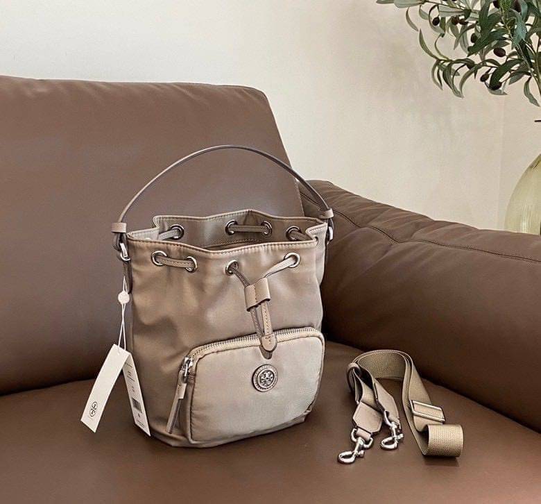 Tory Burch Virginia Nylon Bucket Bag / Tory Burch logo-plaque bucket bag กระเป๋าสะพายทรงบัคเก็ต เปิด-ปิดหนังรูดปากกระเป๋า มีหูหิ้วในตัว คล้องแขนเก๋ๆ ภายในเป็นช่องโล่ง มีช่องย่อย ใส่ของสำคัญจุกจิกได้ มีสายครอส จะสะพายไปไหนก็ได้ทุกโอกาส สวยเลิศทุกสี พร้อมส่