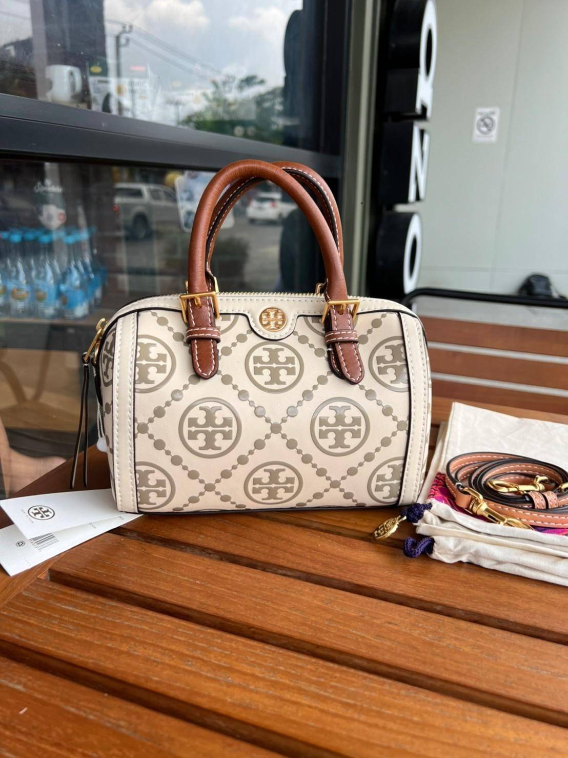 Tory Burch T-Monogram Mini Embossed Wine Bucket Bag / Tory Burch Mini Bucket กระเป๋าถือหรือสะพายไหล่ ทรงหมอนขนาดเล็ก ประดับด้วยลวดลายอันเป็นสัญลักษณ์ของแบรนด์ ถูกประดิษขึ้นด้วยความพิถีพิถันวัสดุหนังอย่างดี ด้านในบุด้วยหนังไมโครซูแอคเนื้อนุ่มทำความสะอาดง่า