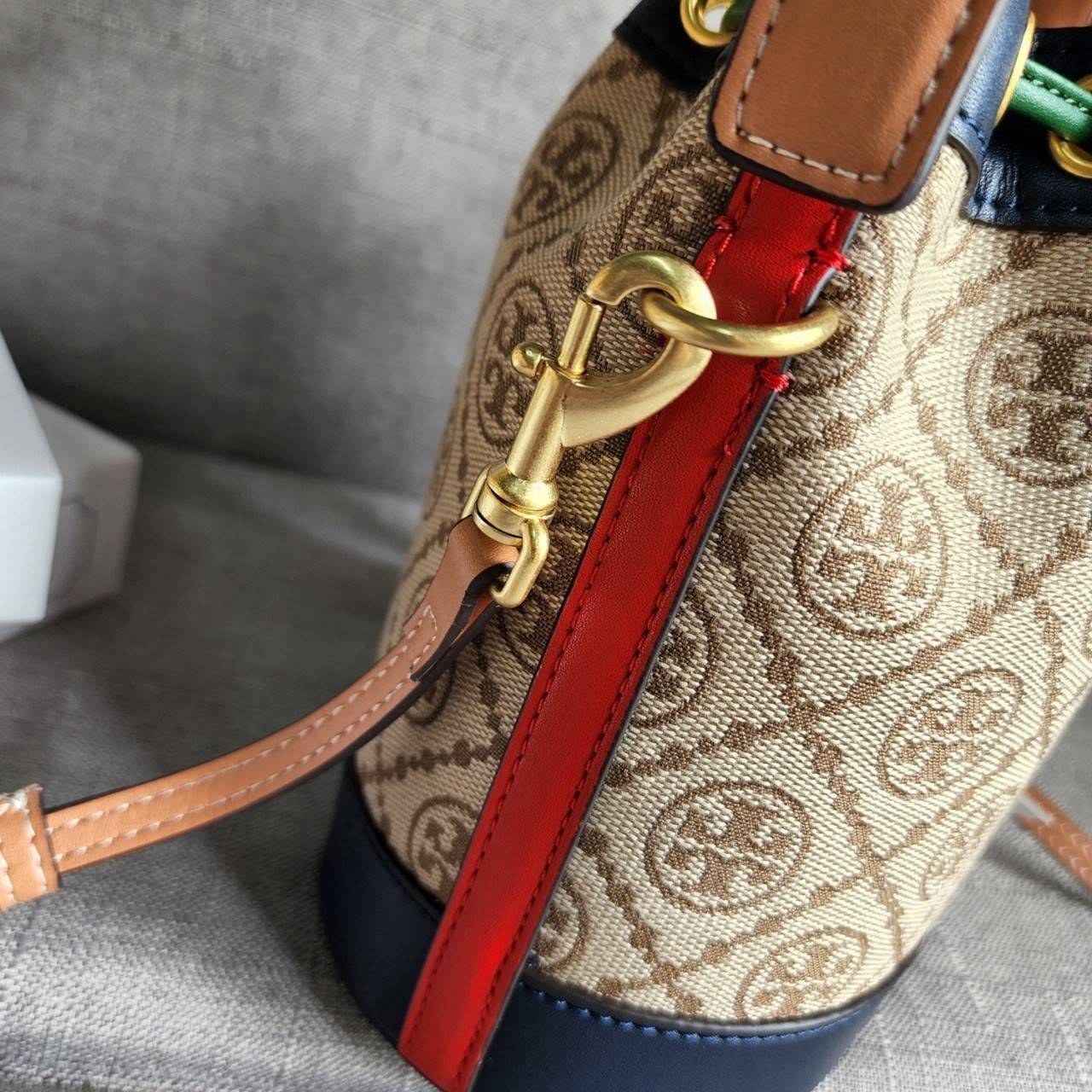 TORY BURCH T MONOGRAM COLORBlOCK JACQUARD MINI BUCKET BAG คอลเลคชั่นใหม่ล่าสุด ครอบครองก่อนใคร รุ่นบัคเก็ตทรงจีบ วัสดุ jacquard สลับหนังแท้ ตัดขอบข้างสีแดงทำให้ดูโดดเด่น หูจับหนังแท้ เปิด ปิด แบบหูรูด ภายในช่องโล่งกว้าง มาพร้อมสายสะพายข้างหนังแท้ ปรับระดั