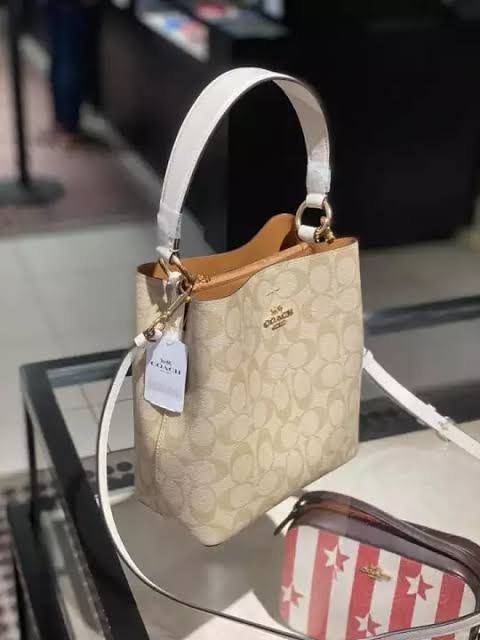 COACH SMALL TOWN BUCKET BAG IN SIGNATURE สำหรับสาวแฟชั่นที่ชอบรายละเอียดชิคๆ ดีไซน์สุดเก๋ แนะนำเลยสำหรับกระเป๋าทรงบักเก็ตใบนี้ เชื่อว่าสาว ๆ หลายคนชื่นชอบ เป็นไอเทมที่สามารถแมทช์ได้กับเสื้อหลากหลายสไตล์ บรรจุของได้เยอะโดยที่กระเป๋าไม่เสียทรง แบ่งช่องใช้งา