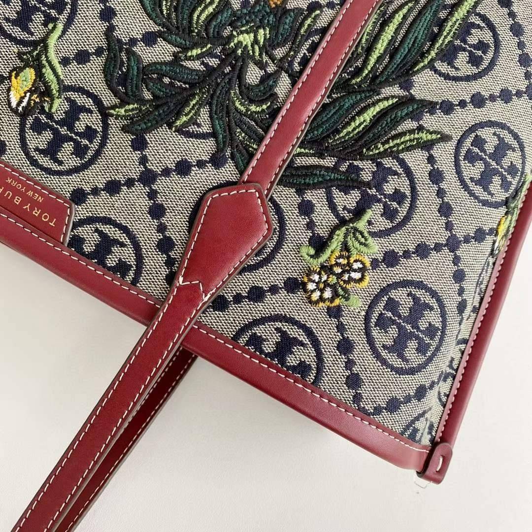 Tory Perry Embroidered T Monogram Triple Compartment Tote Bag เป็นแพทเทิร์นที่ได้รับแรงบันดาลใจจากการควิลท์สไตล์เพนซิลเวเนียดัตซ์ดั้งเดิมและเฉลิมฉลองโลโก้อันเป็นสัญลักษณ์ของแบรนด์ วัสดุผ้าแจ็คการ์ดแบบทอหนัง อะไหล่ทอง โดดเด่นด้วยลายเสือชีร์ต้าร์ งานเย็บปัก
