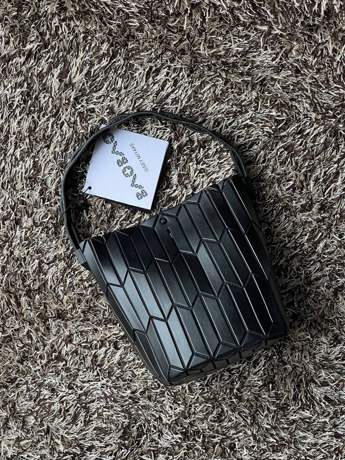 Small : BAO BAO ISSEY MIYAKE SMALL BUCKET เป็นกระเป๋าบัคเก็ตขนาดเล็กสามารถใช้ใส่กระเป๋าสตางค์และโทรศัพท์มือถือได้ ซีรีย์ใหม่นี้มีจุดเด่นที่แผ่นรูปทรงสี่เหลี่ยมด้านขนานในแนวตั้ง เกิดเป็นรูปทรงสามมิติซึ่งแตกต่างไปจากรูปทรงที่เกิดขึ้นจากแผ่นสามเหลี่ยม หูหิ้ว