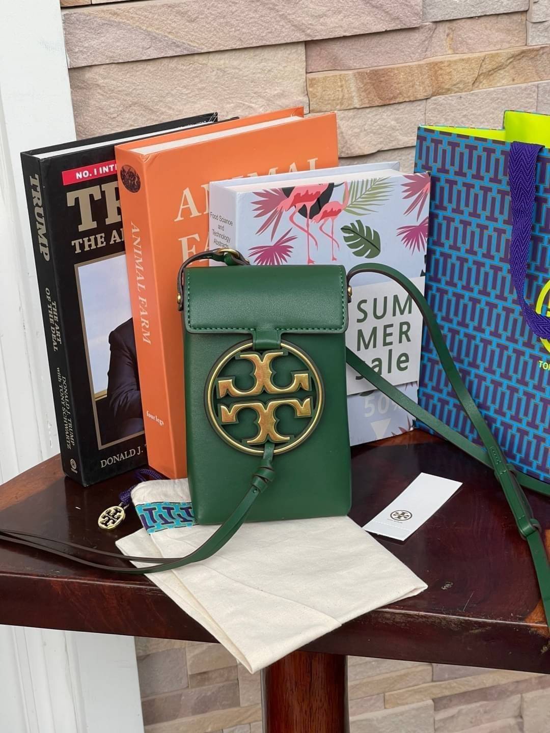 TORY BURCH MILLER METAL PHONE CROSSBODY อีกหนึ่งกระเป๋าใส่มือถือรุ่นฮิตที่เชื่อว่าหลาย ๆ คนต้องเคยเห็นผ่าน ๆ ตามาอย่างแน่นอน กับแบรนด์ Tory Burch ดีไซน์กระเป๋าทรงฝาพับแม่เหล็กใช้งานง่าย มาพร้อมดีเทล Logo แบรนด์โดดเด่นสีทองตัดกับหนังแกะสีดำ ดูหรูดูแพง! แต่