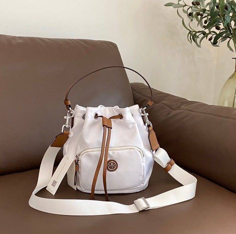 Tory Burch Virginia Nylon Bucket Bag / Tory Burch logo-plaque bucket bag กระเป๋าสะพายทรงบัคเก็ต เปิด-ปิดหนังรูดปากกระเป๋า มีหูหิ้วในตัว คล้องแขนเก๋ๆ ภายในเป็นช่องโล่ง มีช่องย่อย ใส่ของสำคัญจุกจิกได้ มีสายครอส จะสะพายไปไหนก็ได้ทุกโอกาส สวยเลิศทุกสี พร้อมส่