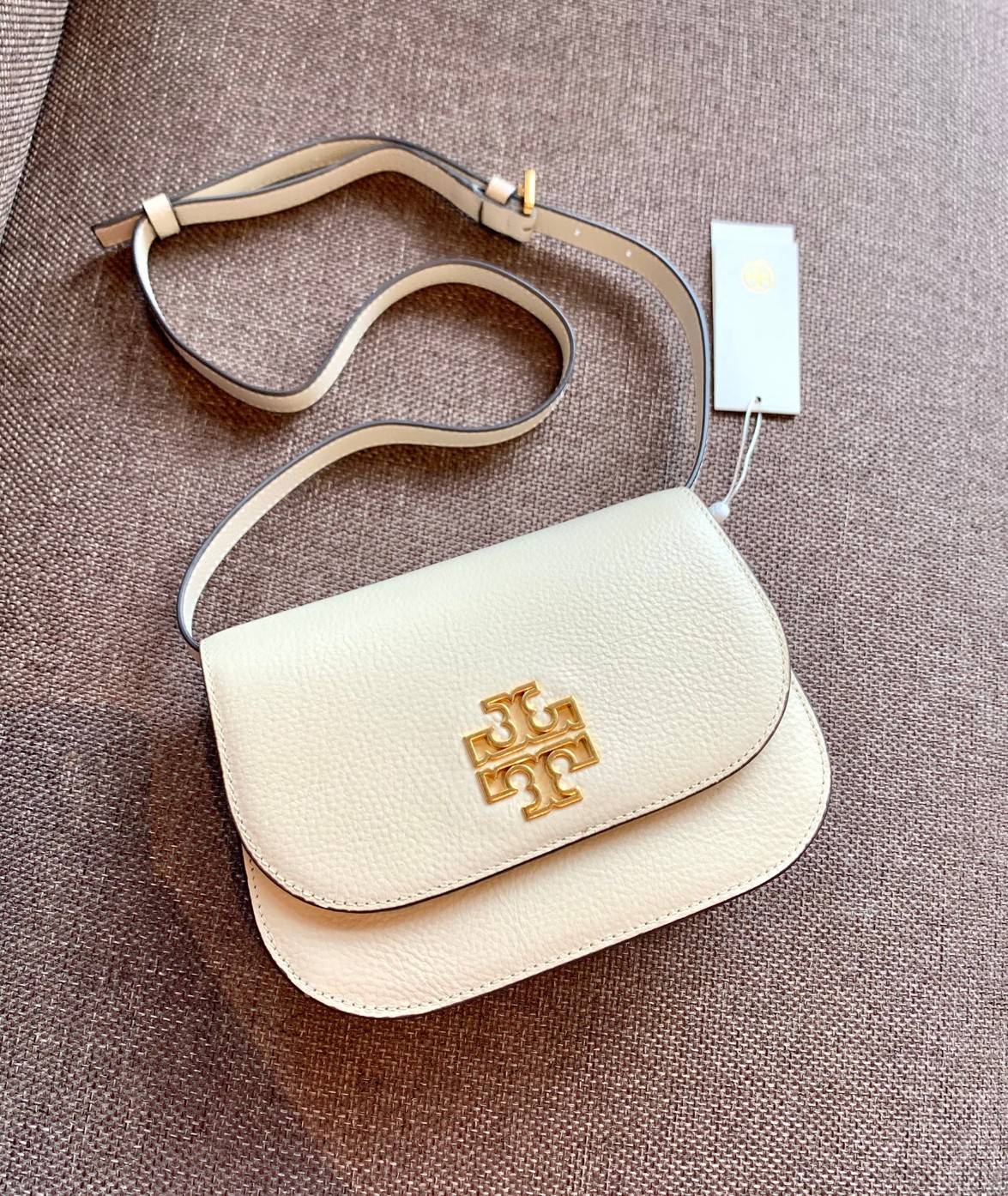TORY BURCH BRLTTEN SMALL SADDLE BAG / Tory Burch Britten Flap Shoulder Bag กระเป๋าสะพายข้าง วัสดุหนังแกะแท้ ด้านหน้าประดับโลโก้แบรนด์ เปิด-ปิดกระเป๋าแบบกระดุมแป็กแม่เหล็กแน่นหนา ภายในมีช่องหลัก ใส่กระเป๋าเงินใบกลาง มือถือได้ทุกรุ่น มีช่องแยกใส่ของจุกจิกอี