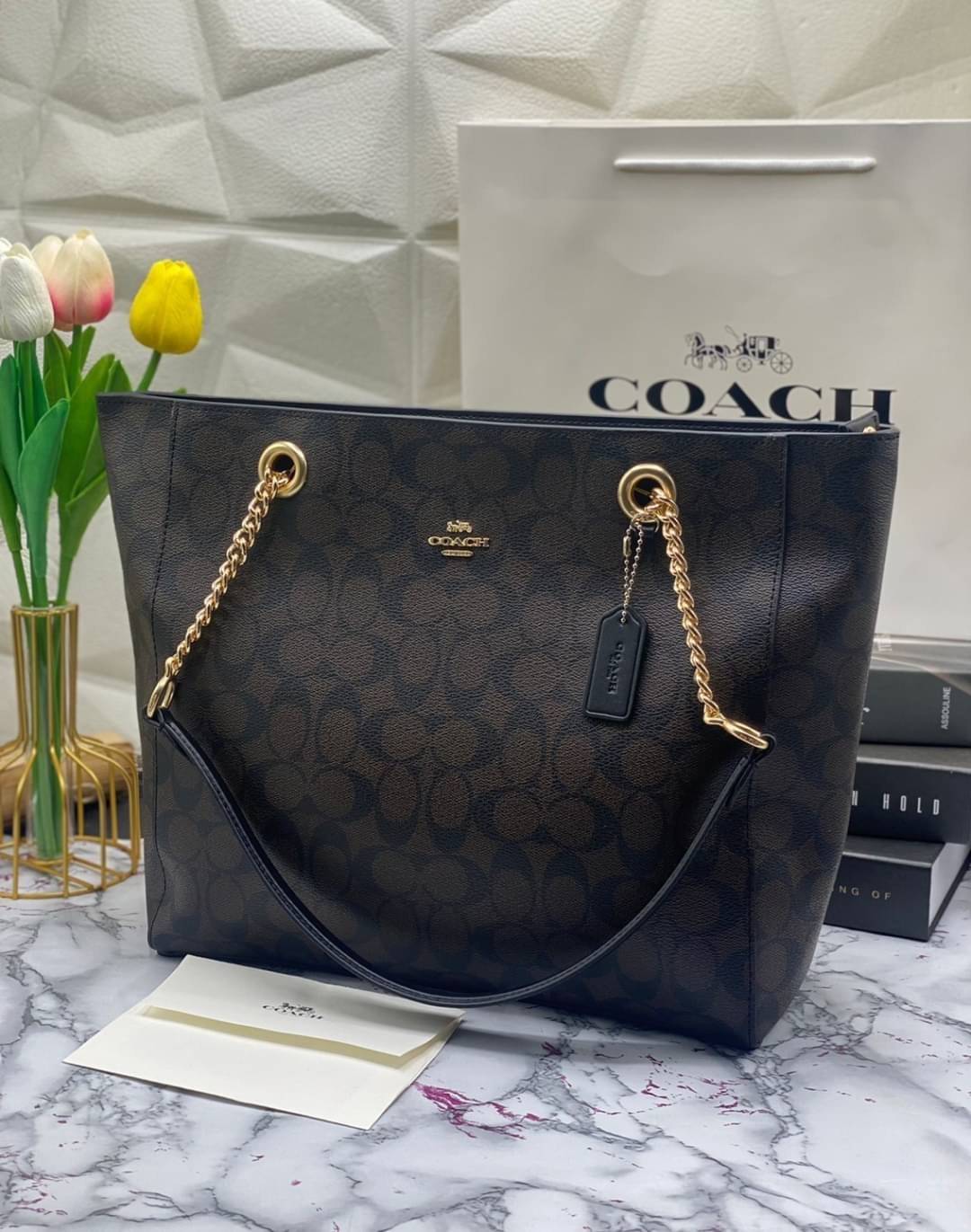 COACH Tote in Signature Canvas Bag กระเป๋าสะพายทรงช้อปปิ้ง สายกระเป๋าเป็นหนังสลับโซ่ทองสวยงาม เพิ่มความหรูหรา ภายในโล่งกว้างใส่ของได้เยอะมาก วัสดุ Canvas เคลือบลายซิกเนเจอร์และหนัง พร้อมซิปกลางเก็บของได้มิดชิดเลยค่ะ มี 3 สี น้ำตาล ดำ ขาว