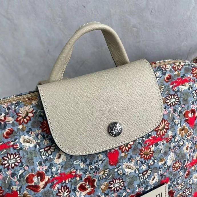 Longchamp X Eu Backpack กระเป๋าเป้สะพายหลังลายดอกๆไม้ วัสดุผ้าฝ้าย อะไหล่สีดำ กระเป๋าเป้แบบลำลองสำหรับสตรีซึ่งนำรูปทรงอันเป็นเอกลักษณ์ของ Le Pliage มาปรับใช้กับทุกสถานการณ์ อุปกรณ์เสริมที่ใช้งานได้จริงนี้มีสายรัดปรับระดับได้และที่จับช่วยให้ สะพายข้างหรือส