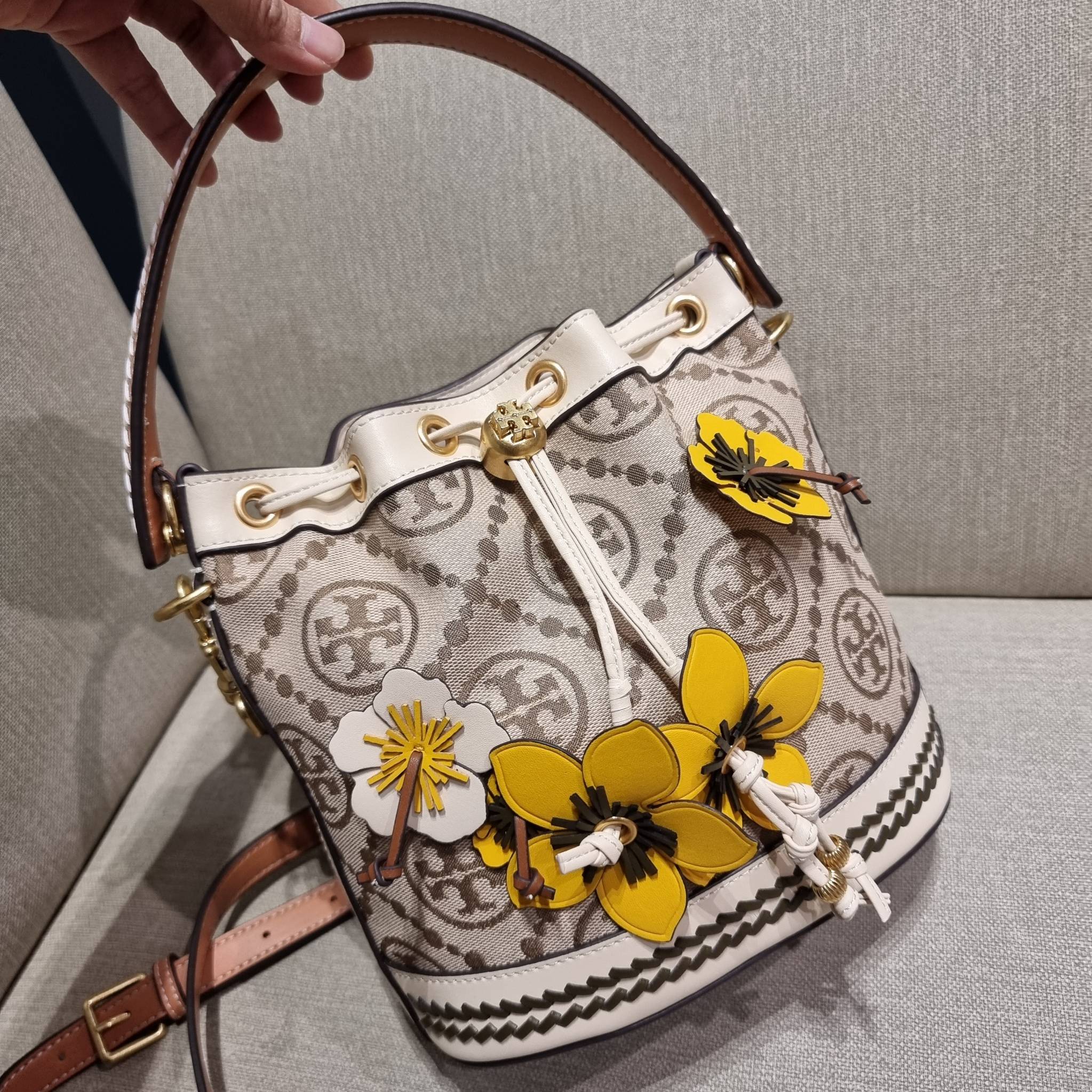 TORY BURCH T MONOGRAM FLORAL BUCKET BAG คอลเลคชั่นใหม่ พร้อมเสิร์ฟความสวยให้ถึงบ้าน!! กระเป๋าบัคเก็ตทรงยอดนิยม ดีไซน์ใหม่ล่าสุด สไตล์งานคราฟ มีลูกเล่นประดับดอกไม้กับตัวกระเป๋า และตัวรูดสาย วัสดุผ้า jacquard ตัดสลับหนังแท้ หูจับและขอบกระเป๋าตกแต่งลายสานสวย