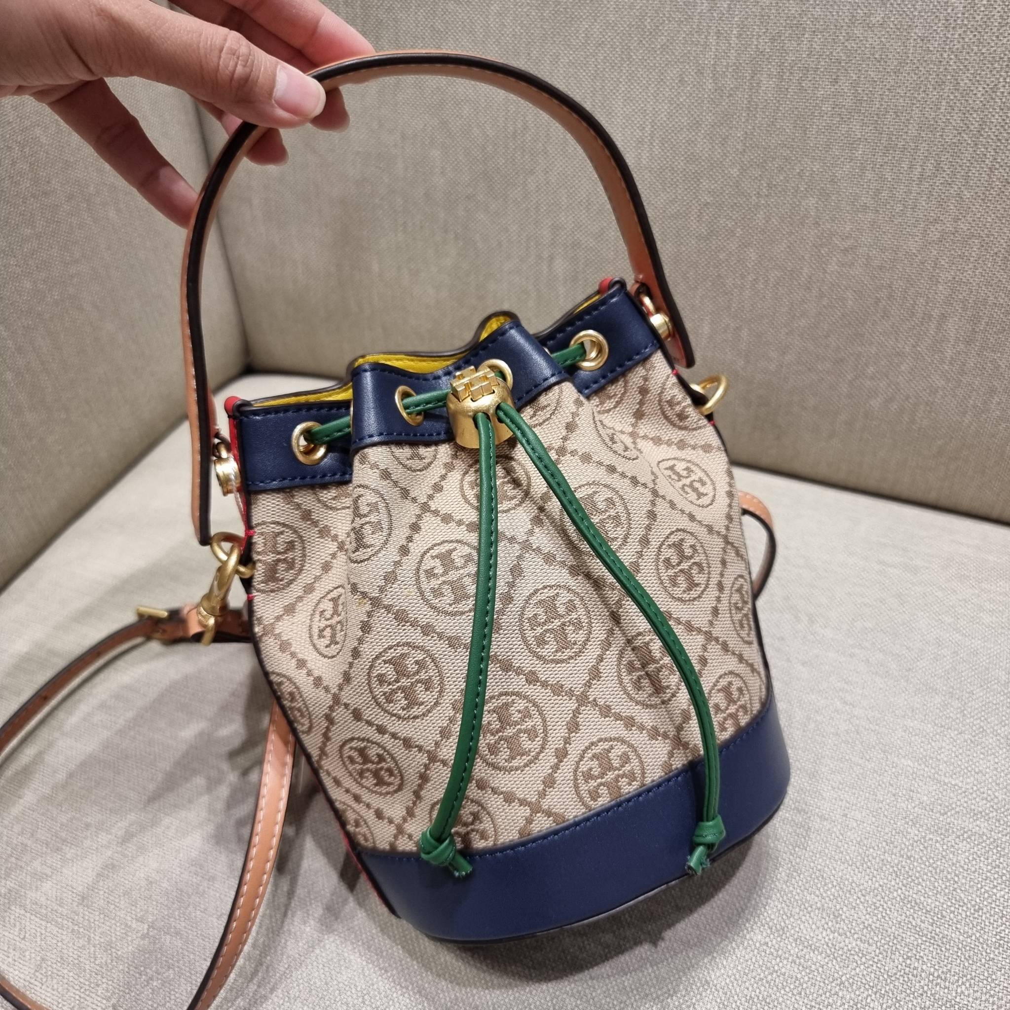 MINI : TORY BURCH T MONOGRAM COLOR-BLOCK JACQUARD MINI BUCKET BAG ใหม่ล่าสุด กับกระเป๋าบัคเก็ตทรงสวย ไซส์มินิ ในราคาน่ารัก โดดเด่นด้วยลวดลายเอกลักษณ์ ผสานลายคัลเลอร์บล็อค โทนสีตัดกันอย่างลงตัว ถักทอบนวัสดุ woven jacquard ลายคมชัด สลับส่วนของหนังแท้ ภายในเ