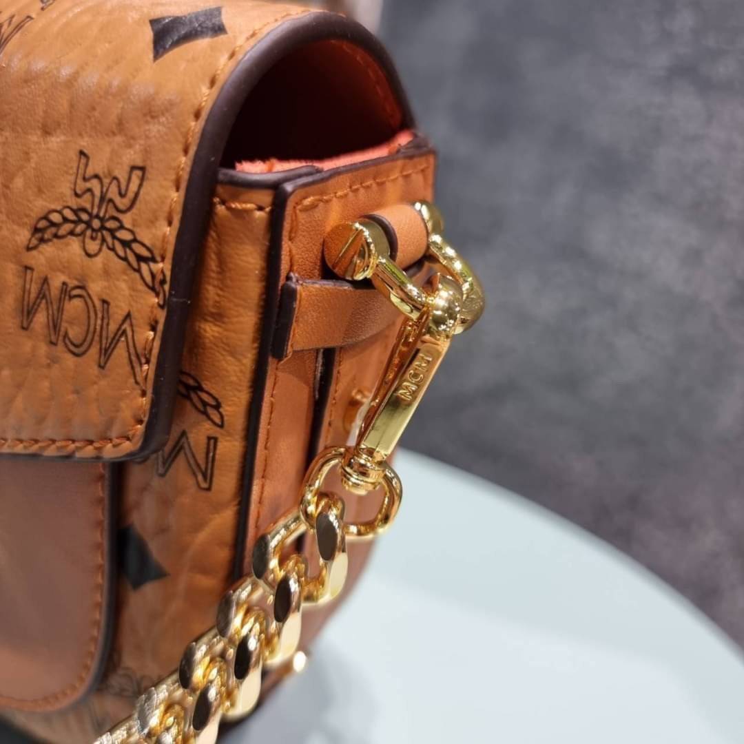 M.C.M MINI PATRICIA CROSSBODY IN VISETOS กระเป๋าสะพายไซส์มินิ แรงดีไม่มีตกน้า คอลเลคชั่นนี้ดีไซน์แปลกใหม่ ทรงโค้งมน สวยหรู ด้านข้างตกแต่งหมุดทองรอบใบ วัสดุตัวกระเป๋าเป็นหนังแคนวาสคุณภาพดี ภายในเป็นหนังกลับสีส้มโดดเด่นเป็นเอกลักษณ์ มีช่องใส่บัตรแยกให้ เปิด